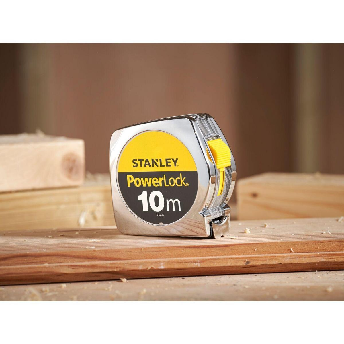 Ein Stanley PowerLock 10m Maßband auf Holz, mit gelb-schwarzem Etikett.