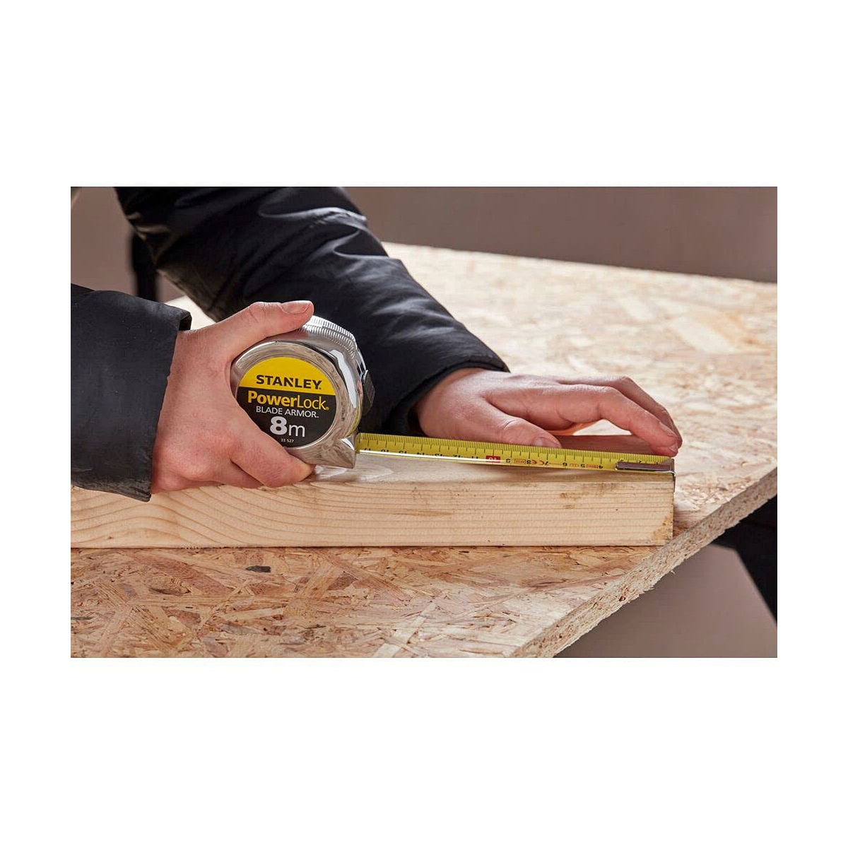 Una persona che usa un metro a nastro Stanley PowerLock BladeArmor da 8 m sul legno.