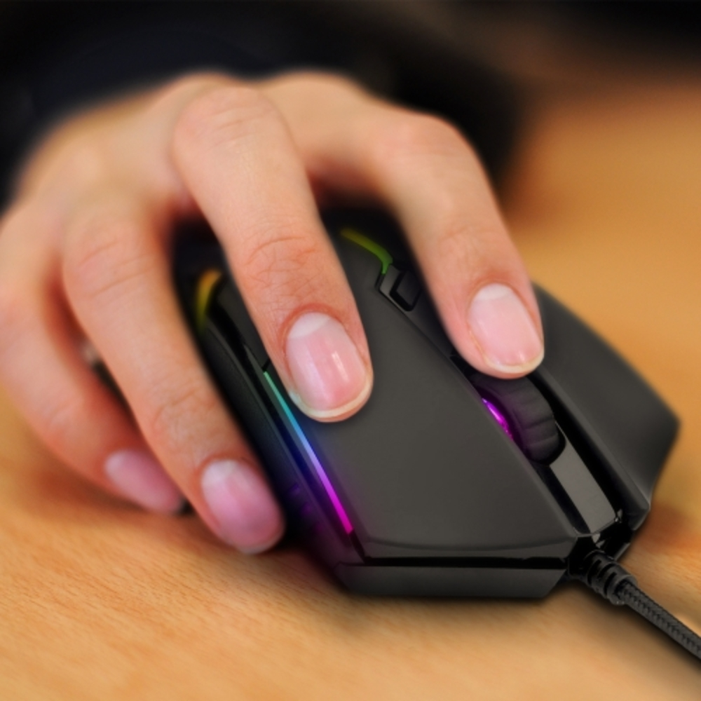 Primo piano di una mano che usa un mouse da gioco nero con illuminazione RGB su un tavolo di legno.