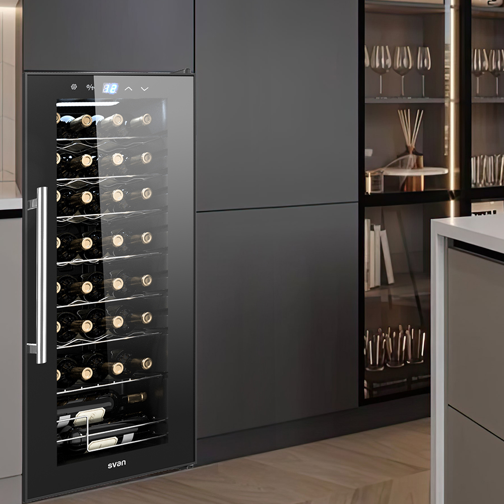 Vinoteca negra en un entorno de cocina. Puerta de cristal, botellas visibles. Cocina moderna, tonos neutros.