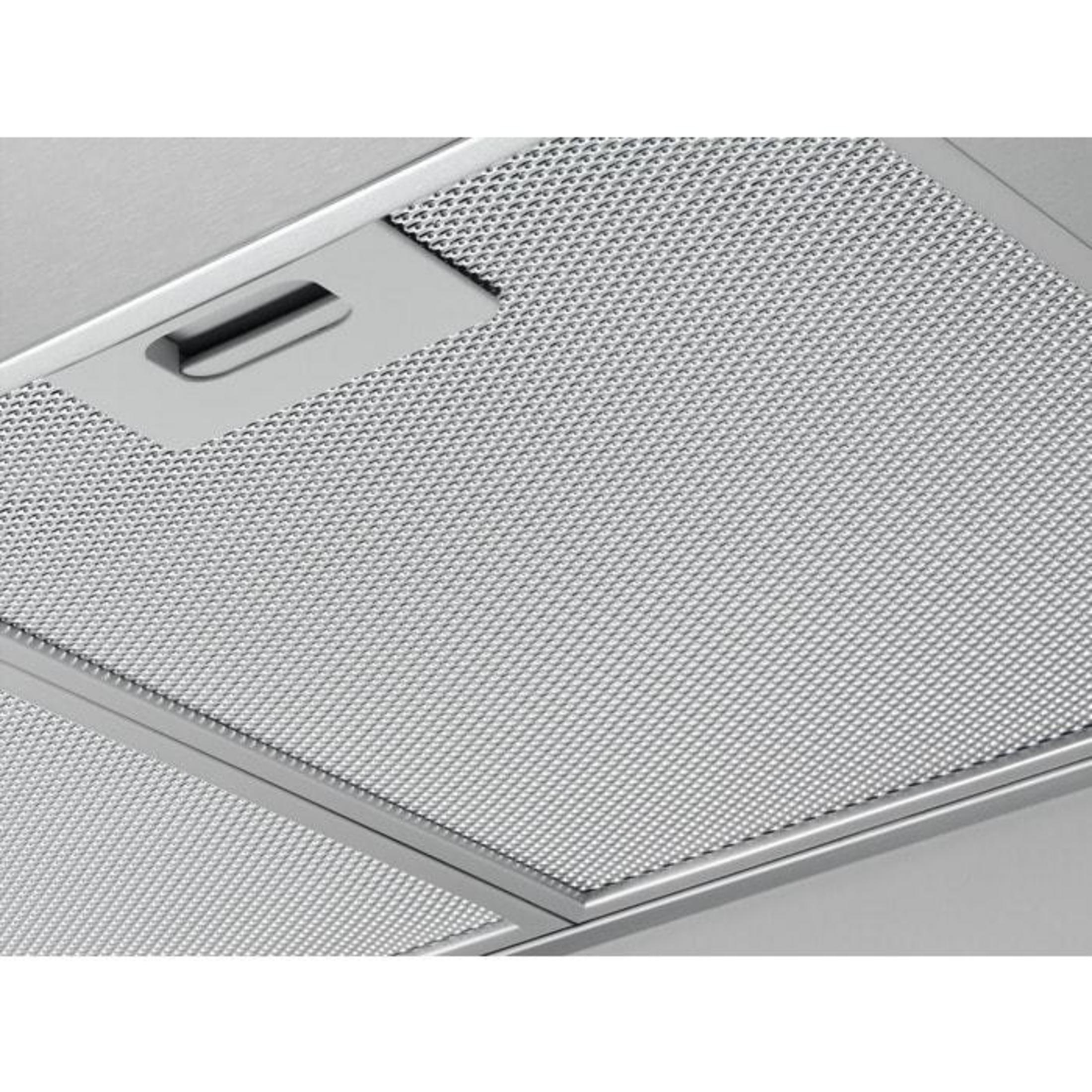 Nahaufnahme eines Metallfilters im Inneren eines Geräts, wahrscheinlich einer Dunstabzugshaube, mit einem Griff.