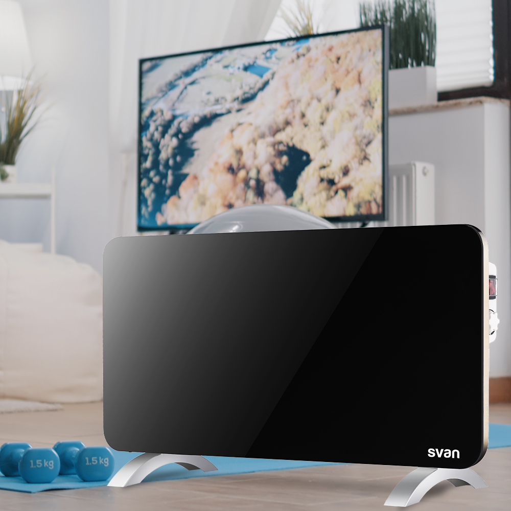 Calentador eléctrico negro con patas plateadas en sala de estar. Pesas azules y TV al fondo.