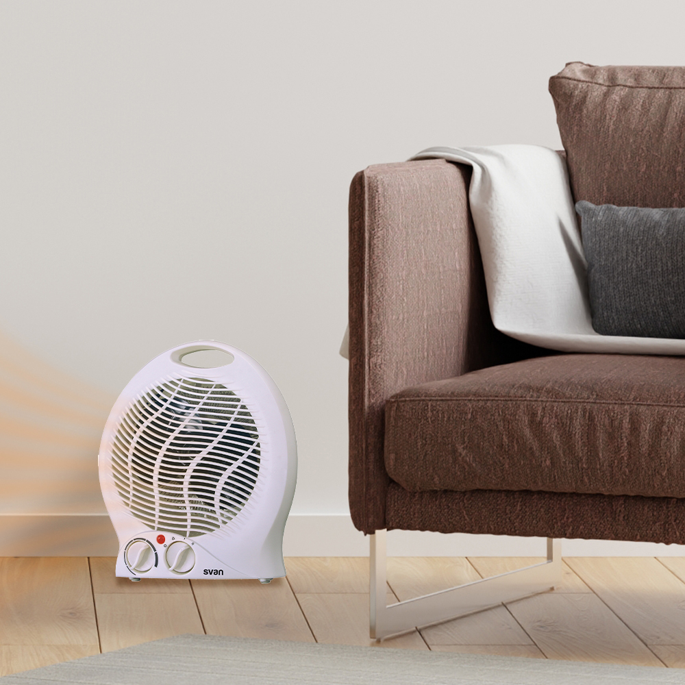 Calentador con ventilador blanco junto a un sofá marrón. Una manta blanca y una almohada gris en el sofá.