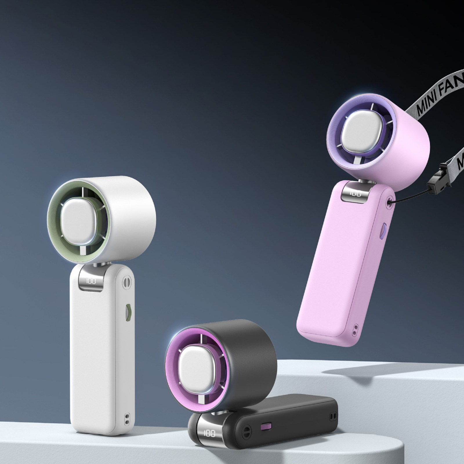 Drei Mini-Ventilatoren: weiß, rosa und schwarz. Jeder hat eine Digitalanzeige und einen Griff. Sie stehen auf einer weißen Oberfläche.