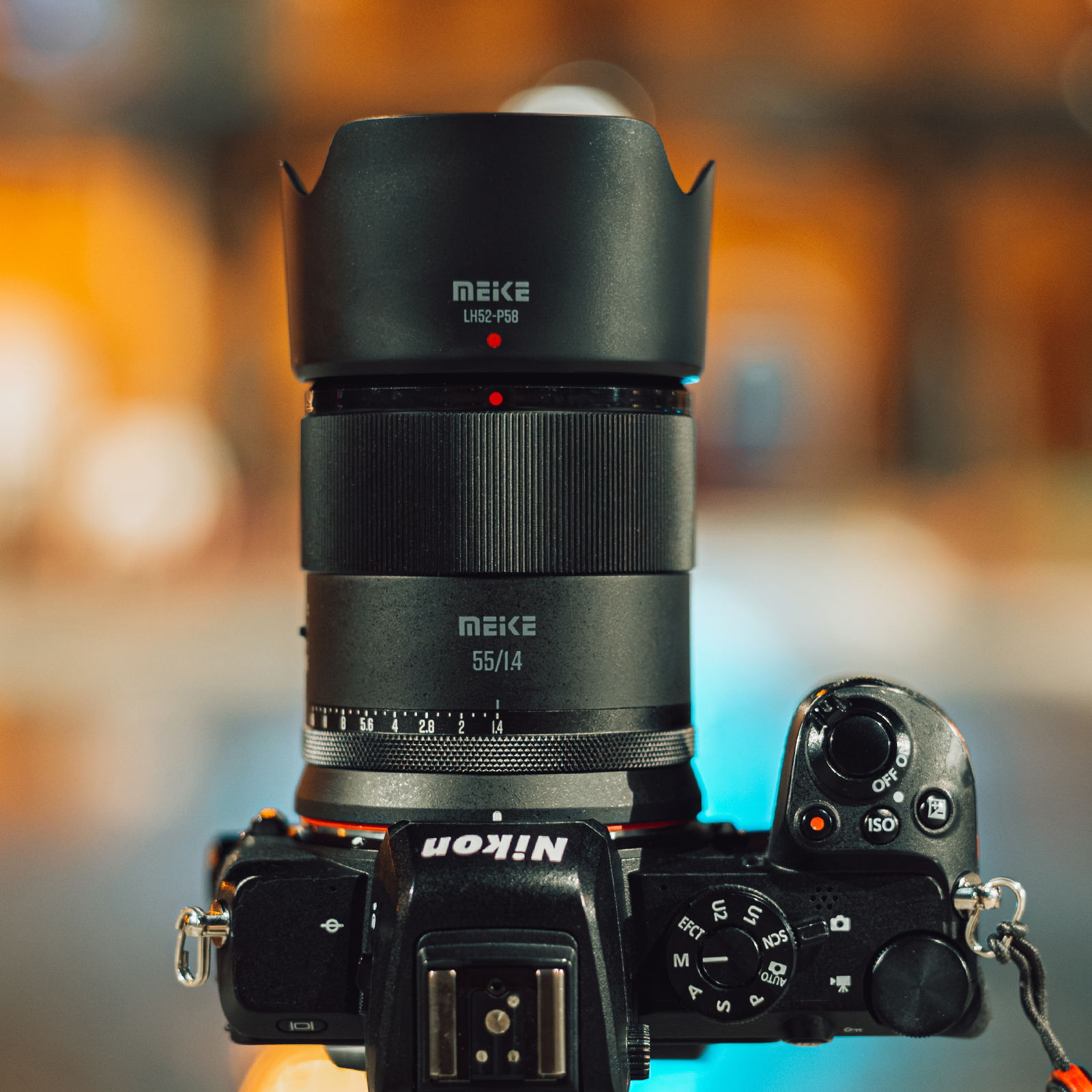 Ein Kameraobjektiv ist an einer Nikon-Kamera befestigt. Das Objektiv ist schwarz und hat Text darauf.