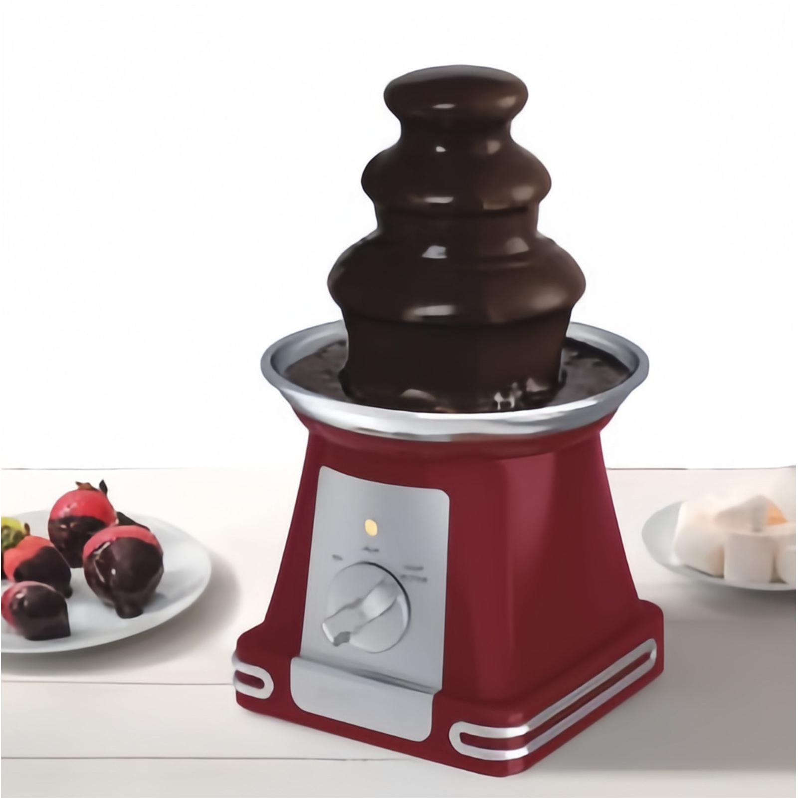 Ein roter Schokoladenbrunnen mit Erdbeeren und Marshmallows auf weißer Oberfläche. Schokolade fließt herunter.