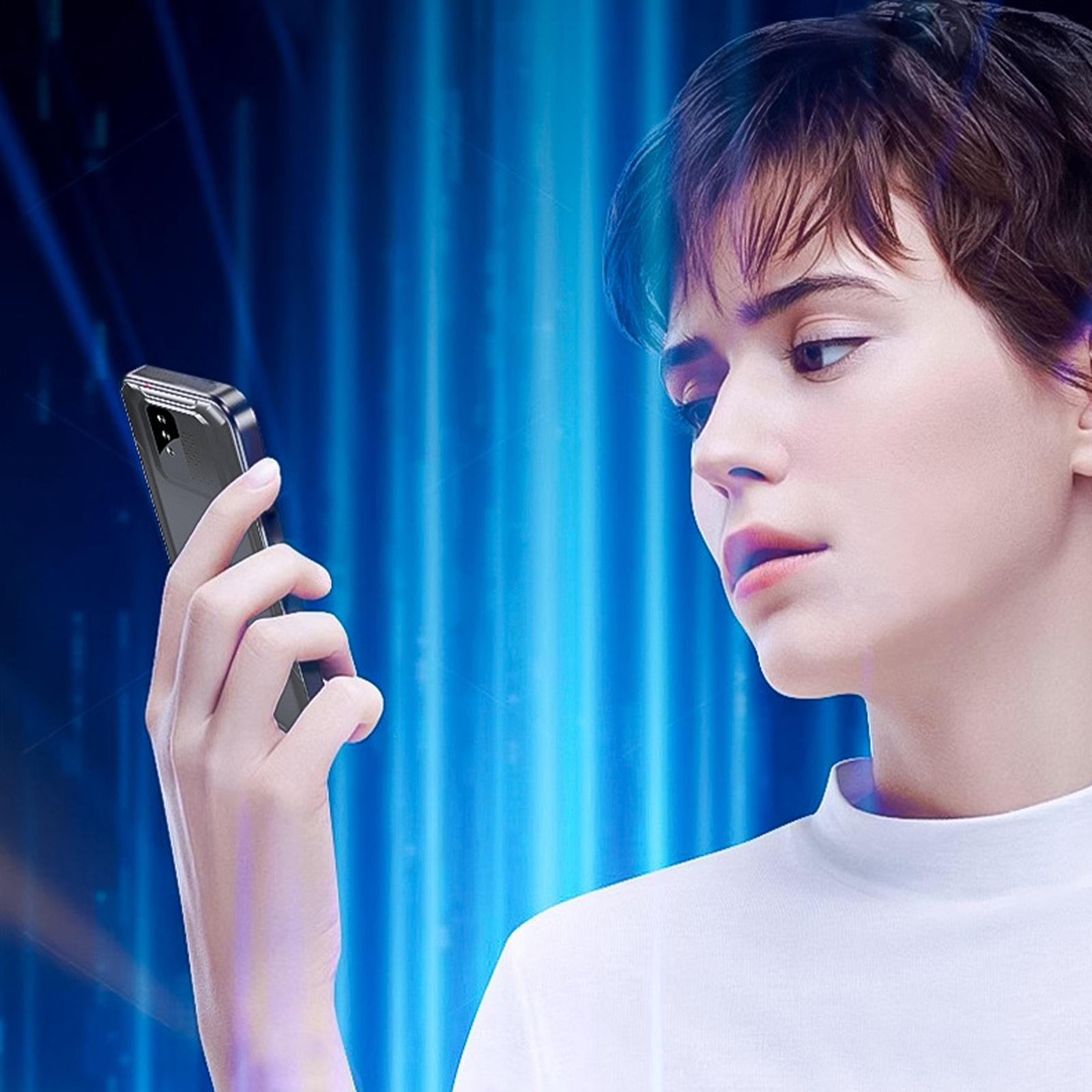 Eine Frau schaut auf ein schwarzes Telefon. Sie trägt ein weißes Hemd und ist vor blauem Hintergrund.