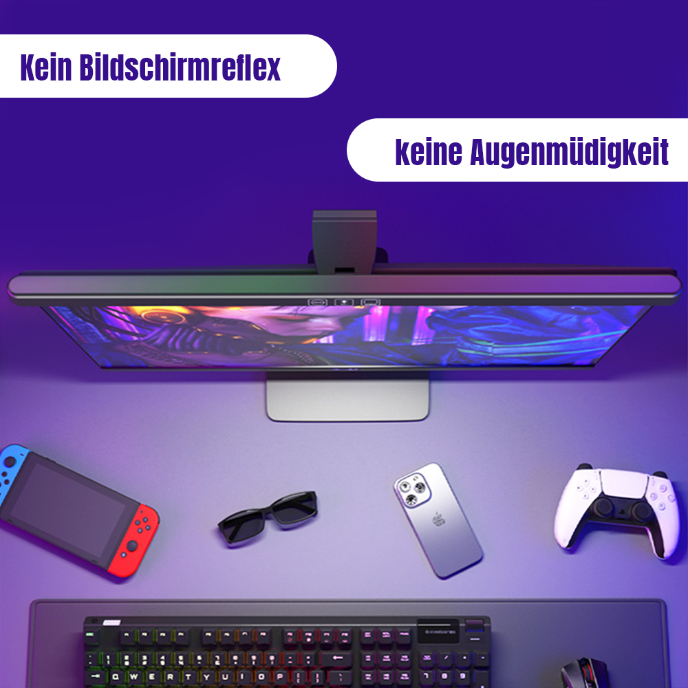 Ein Schreibtisch-Setup mit Monitor, Spielkonsolen und Zubehör. Die Szene wird von einer Schreibtischlampe von oben beleuchtet.