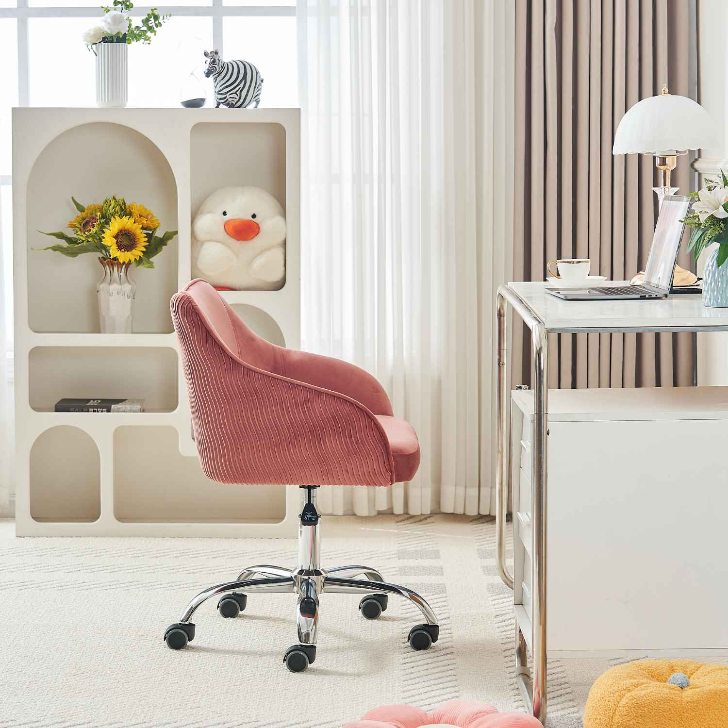 Ein rosa Bürostuhl steht in einem Raum mit einem Schreibtisch und einem weißen Regal mit Dekorationen.
