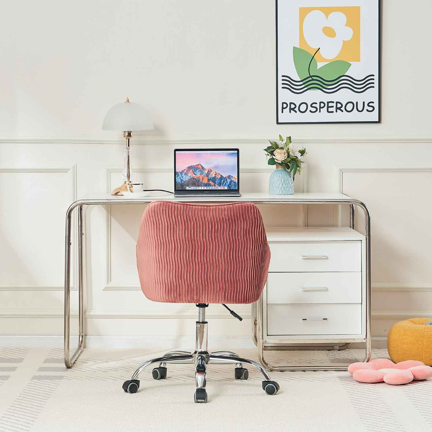 Die Rückseite eines rosa Bürostuhls ist zur Kamera gerichtet. Es gibt einen weißen Schreibtisch mit einem Laptop und einer Zeichnung an der Wand.