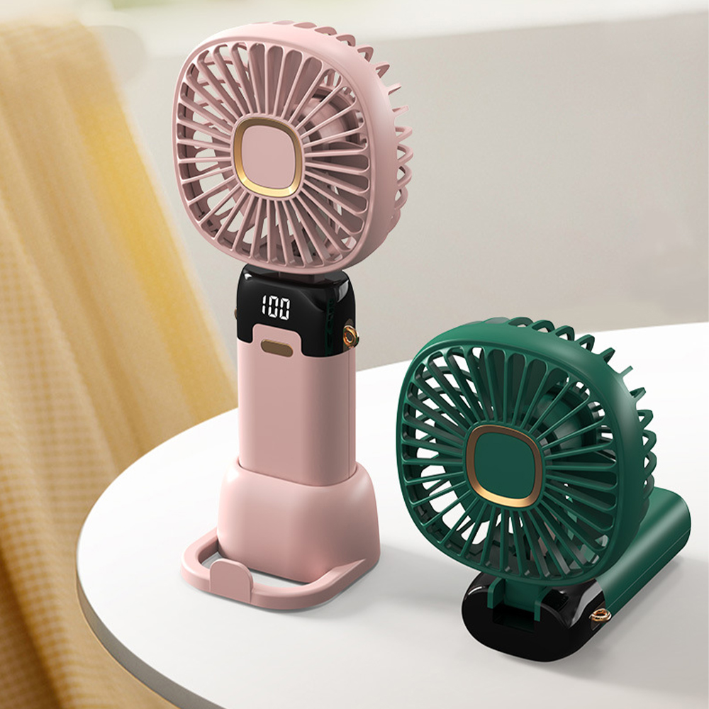 Zwei Handventilatoren, einer rosa, einer grün, auf einem weißen Tisch, mit weißem Hintergrund.