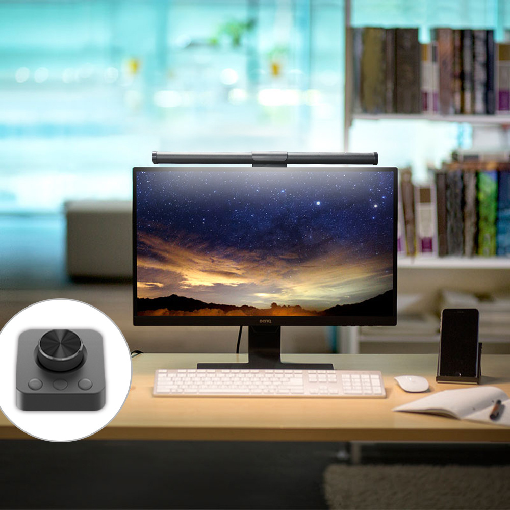 Un'impostazione da scrivania con monitor, tastiera e una lampada da scrivania con pannello di controllo.