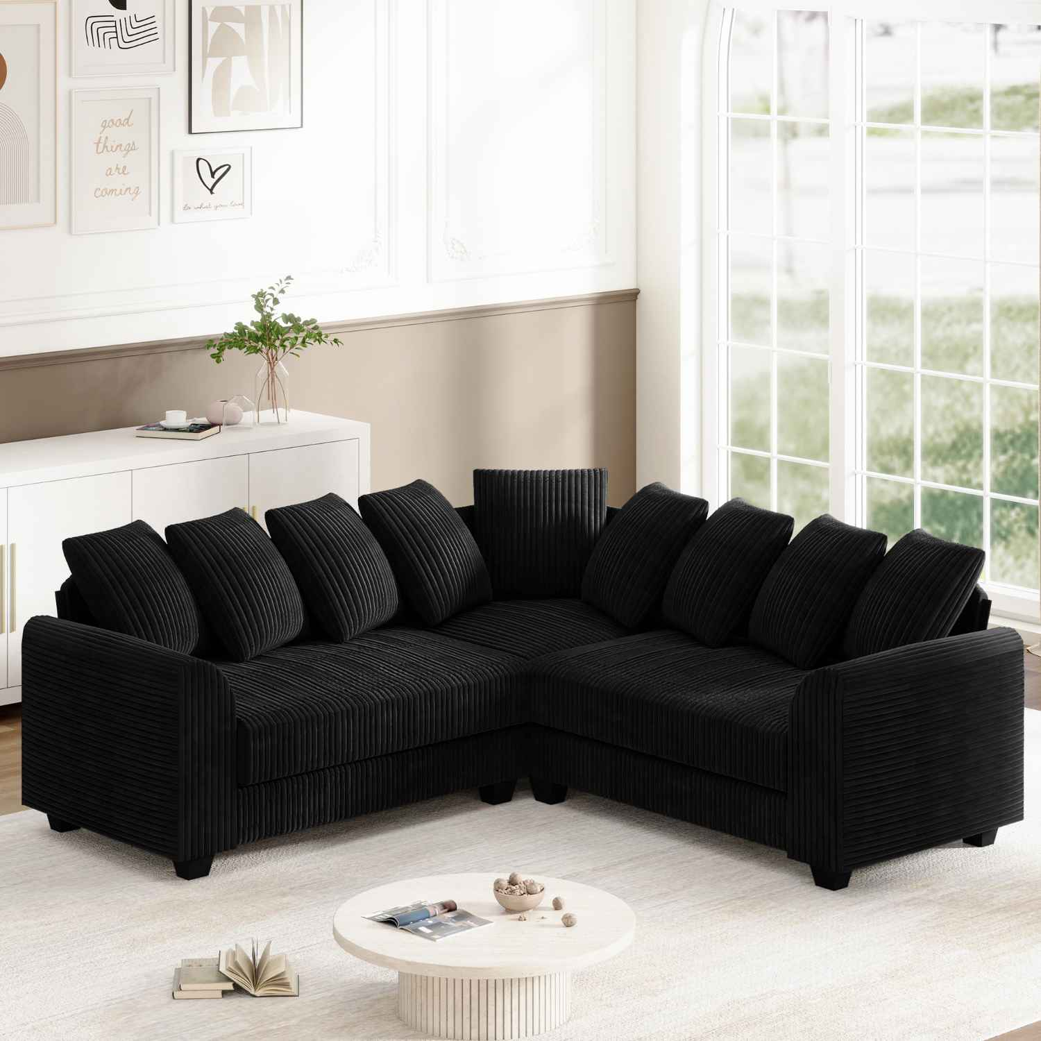 Ein schwarzes, L-förmiges Cordsofa mit Kissen, platziert auf einem hellen Teppich in einem Raum.