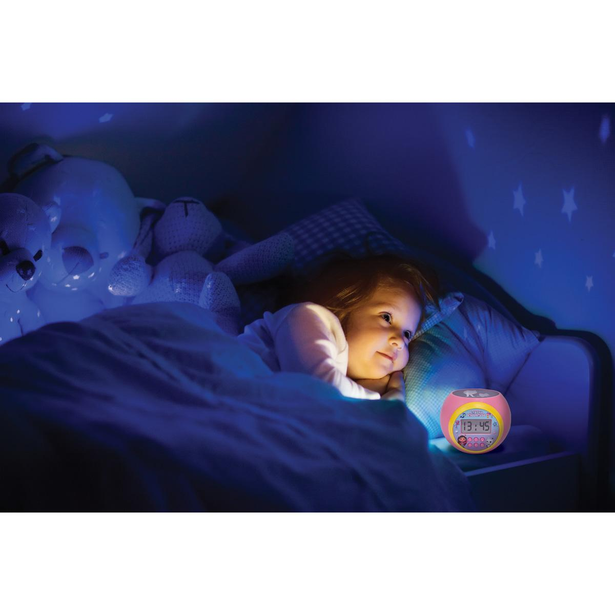 Bambino a letto che guarda un orologio rosa.