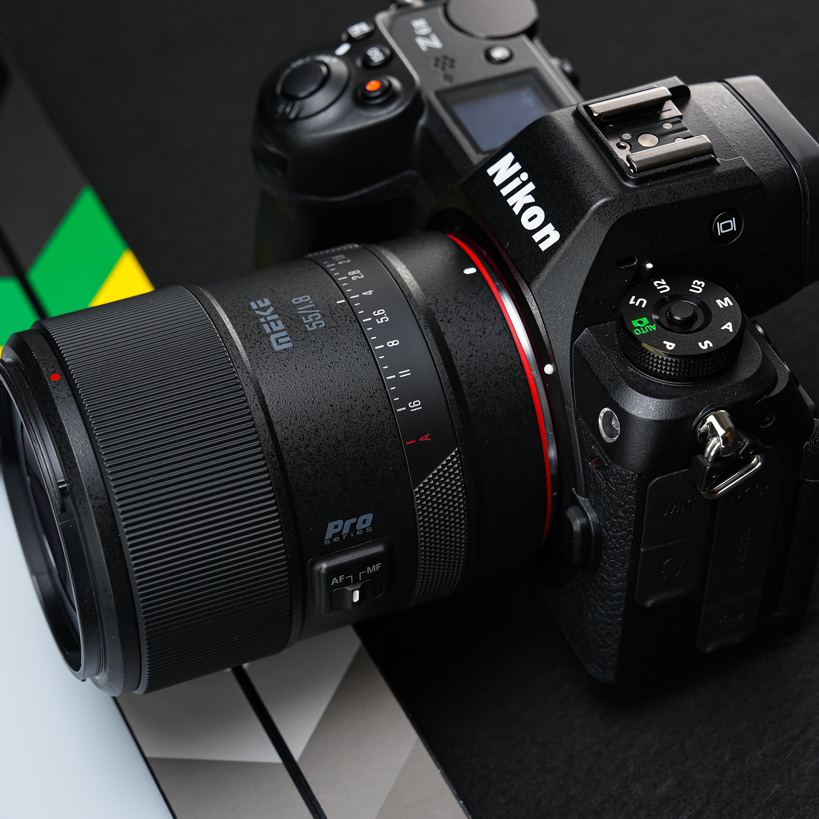 Eine schwarze Kamera mit Objektiv, schräg auf dunkler Oberfläche, mit Nikon-Logo.
