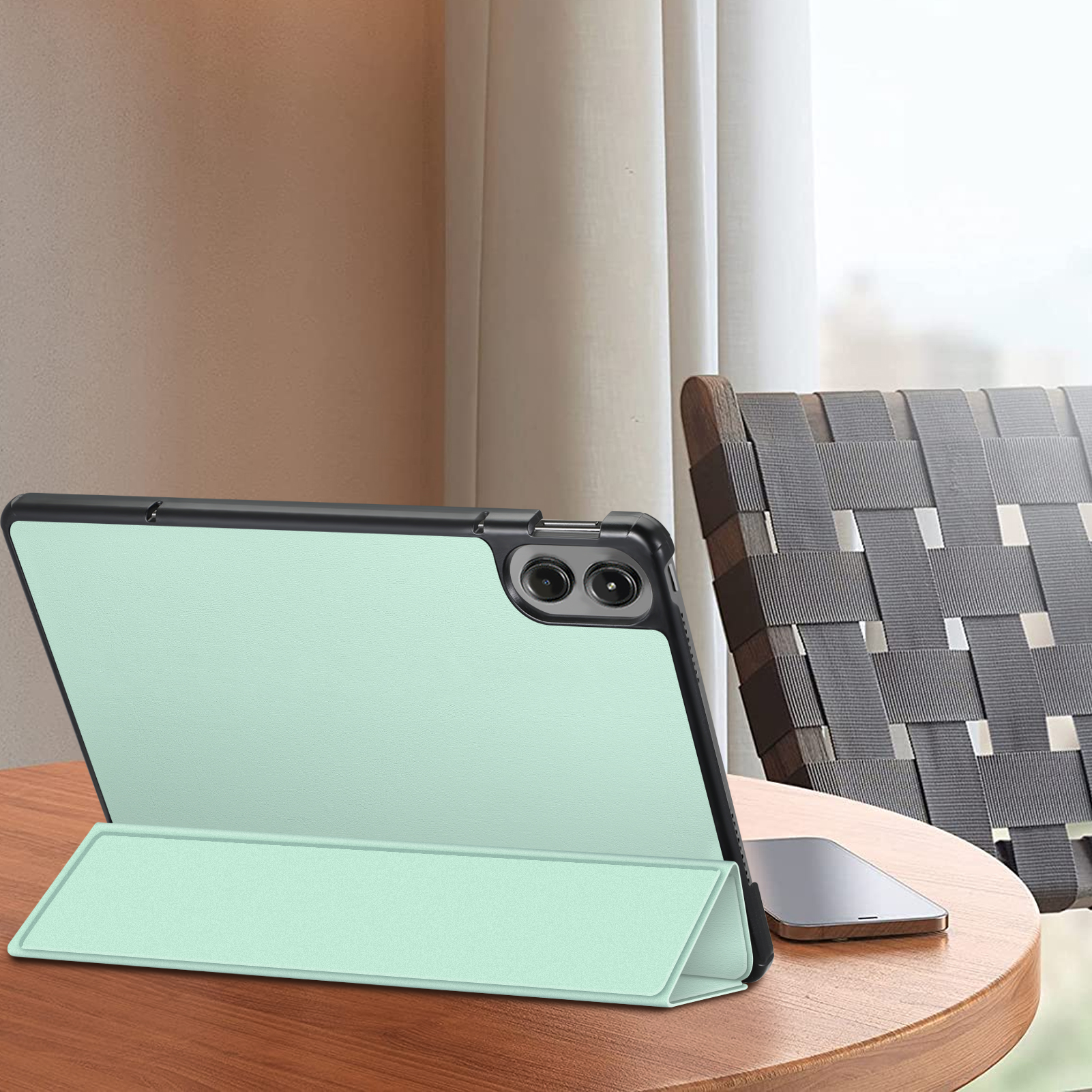 Tablet in mintgrüner Hülle auf einem Tisch. Ein Telefon liegt ebenfalls auf dem Tisch. Im Hintergrund ein Raum.