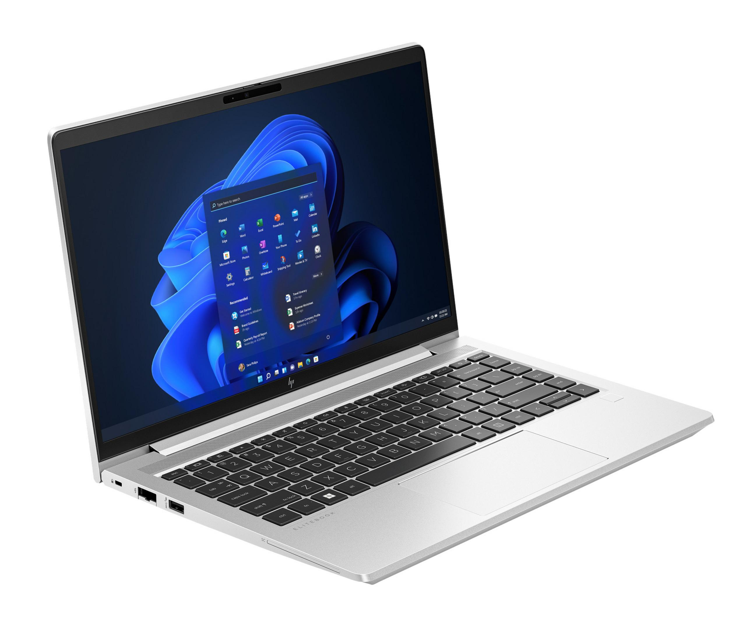 Srebrny laptop z interfejsem Windows 11 na ekranie, otwarty pod kątem. Białe tło.