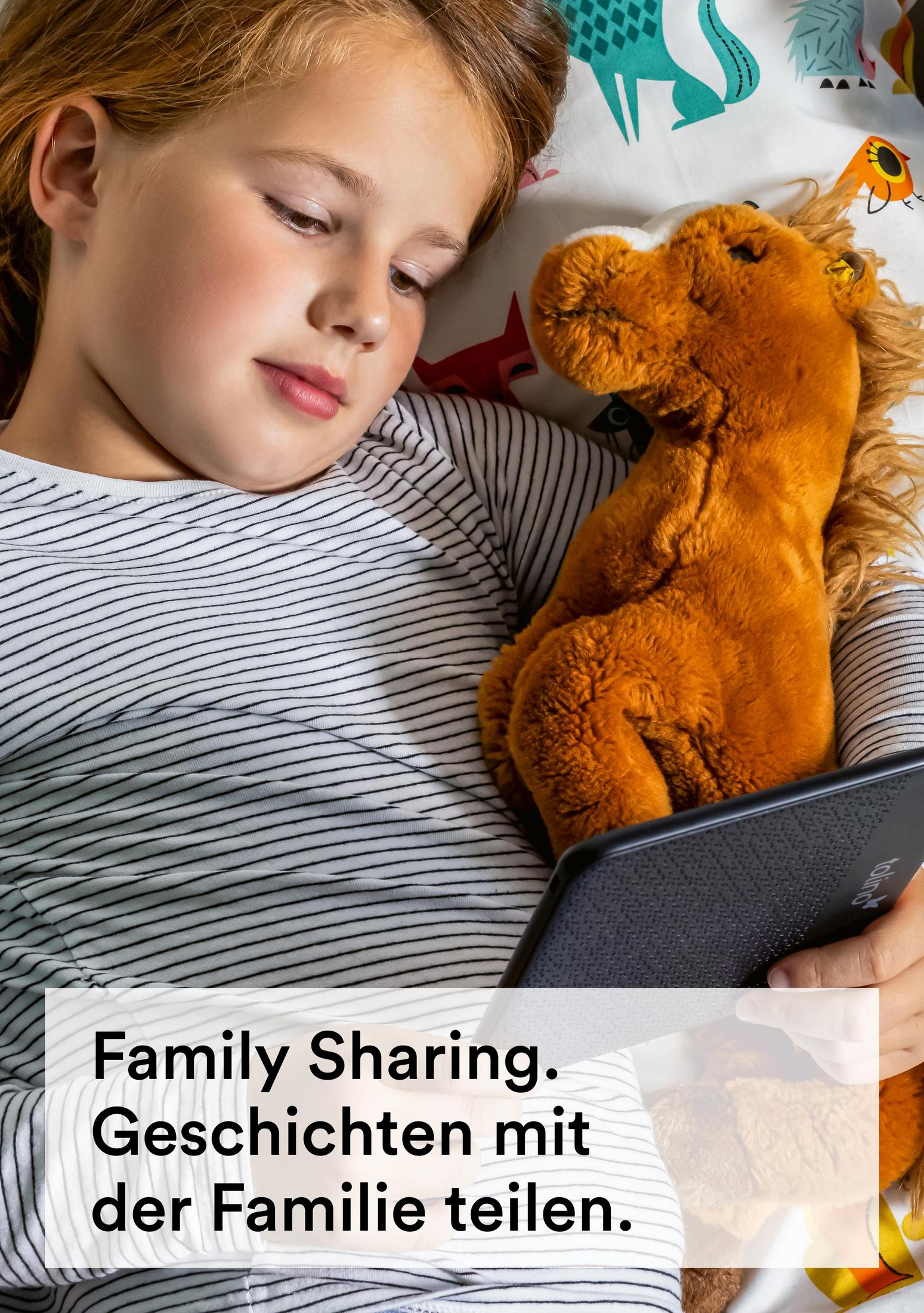 Dziecko czyta na czytniku e-booków, z pluszowym koniem. Tekst: Udostępnianie rodzinne. Dziel się historiami z rodziną.