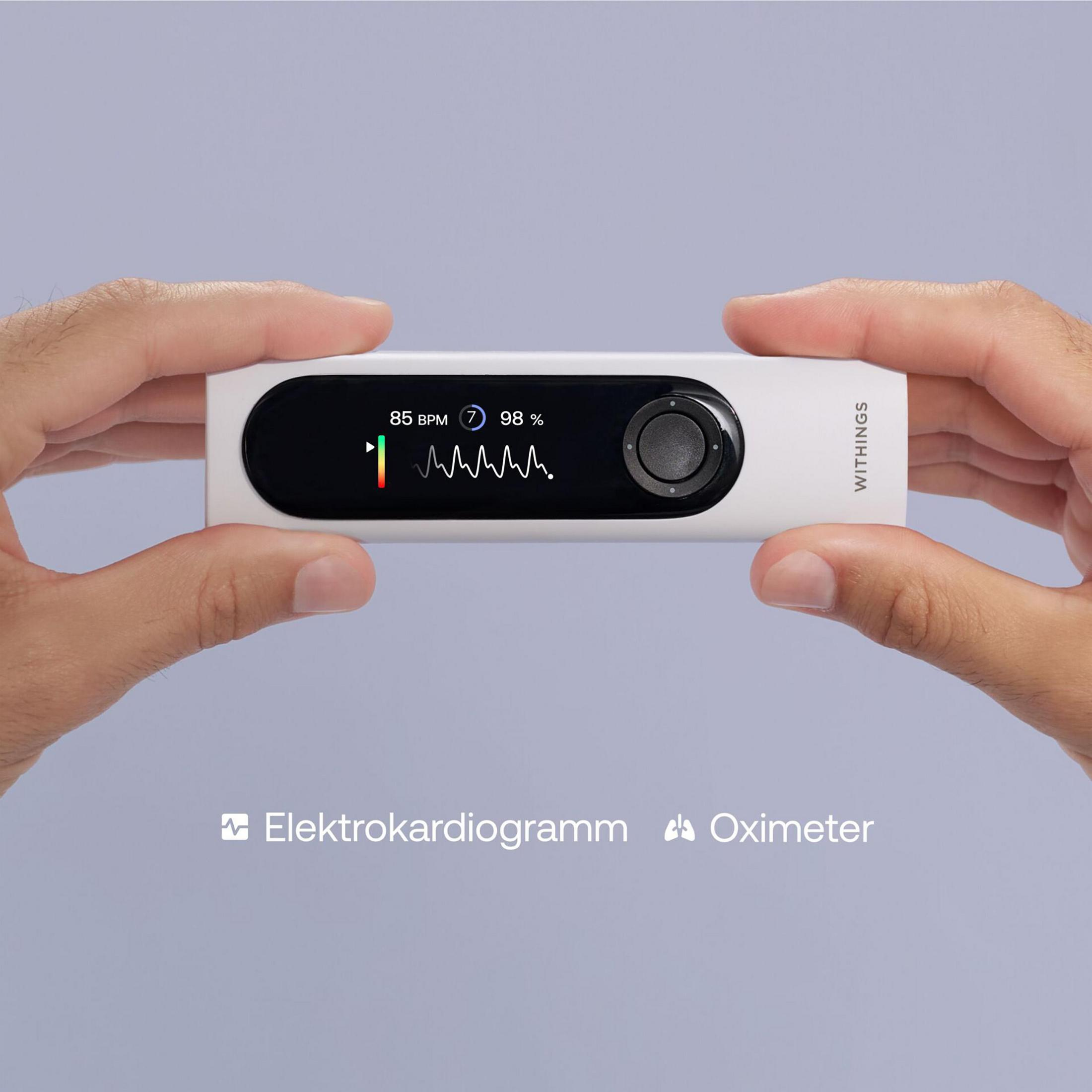 Ręce trzymające białe urządzenie Withings. Urządzenie wyświetla informacje EKG i tętna.