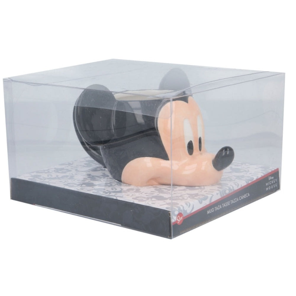 Taza de Mickey Mouse en una caja transparente sobre una base estampada, negro, blanco y beige.