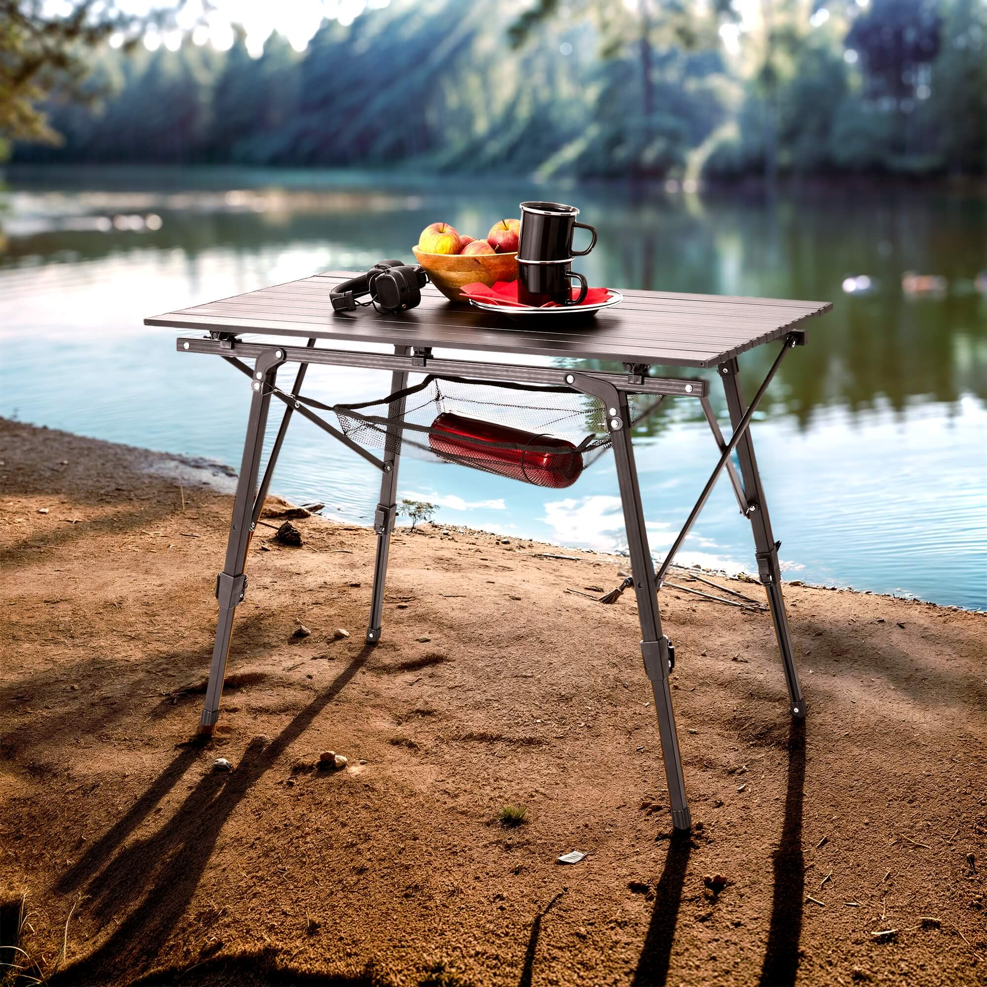 Klapptisch am Strand aufgebaut. Im Hintergrund ein See. Obst und Getränke auf dem Tisch.