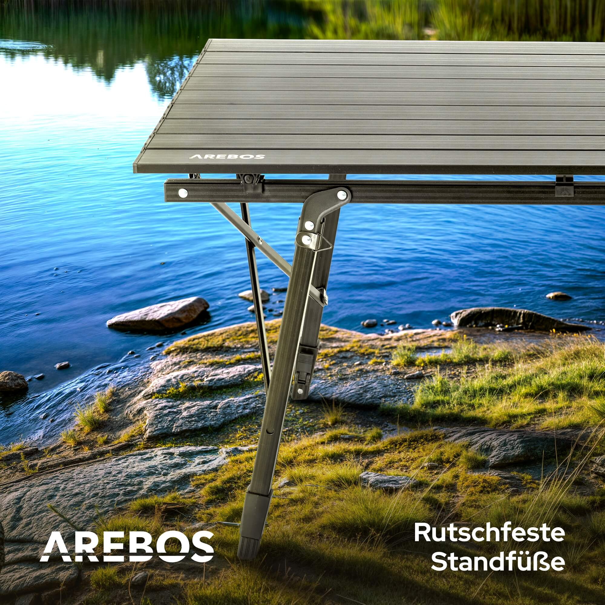 Klapptisch an einem See. Ein Teil des Tischbeins ist hervorgehoben und das AREBOS Logo ist sichtbar.