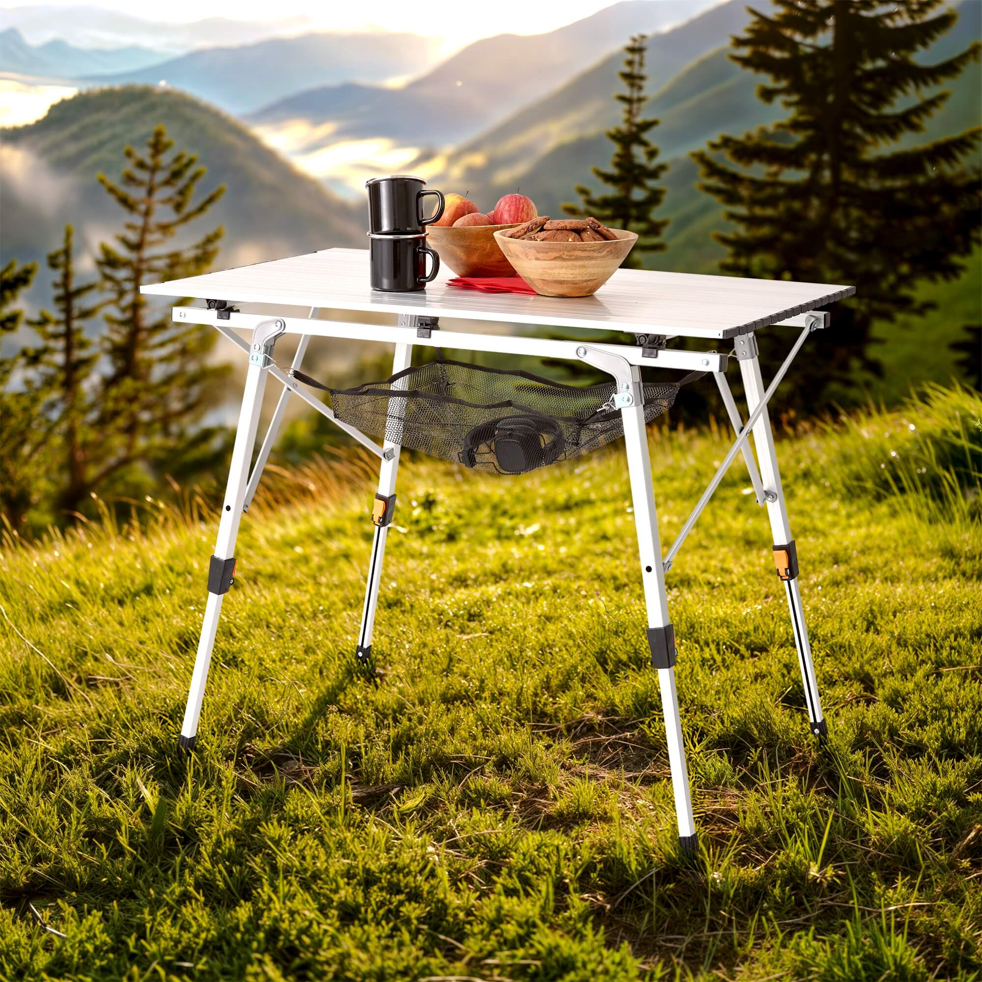 Ein Klapptisch auf Gras mit Essen und Tassen. Berge im Hintergrund.