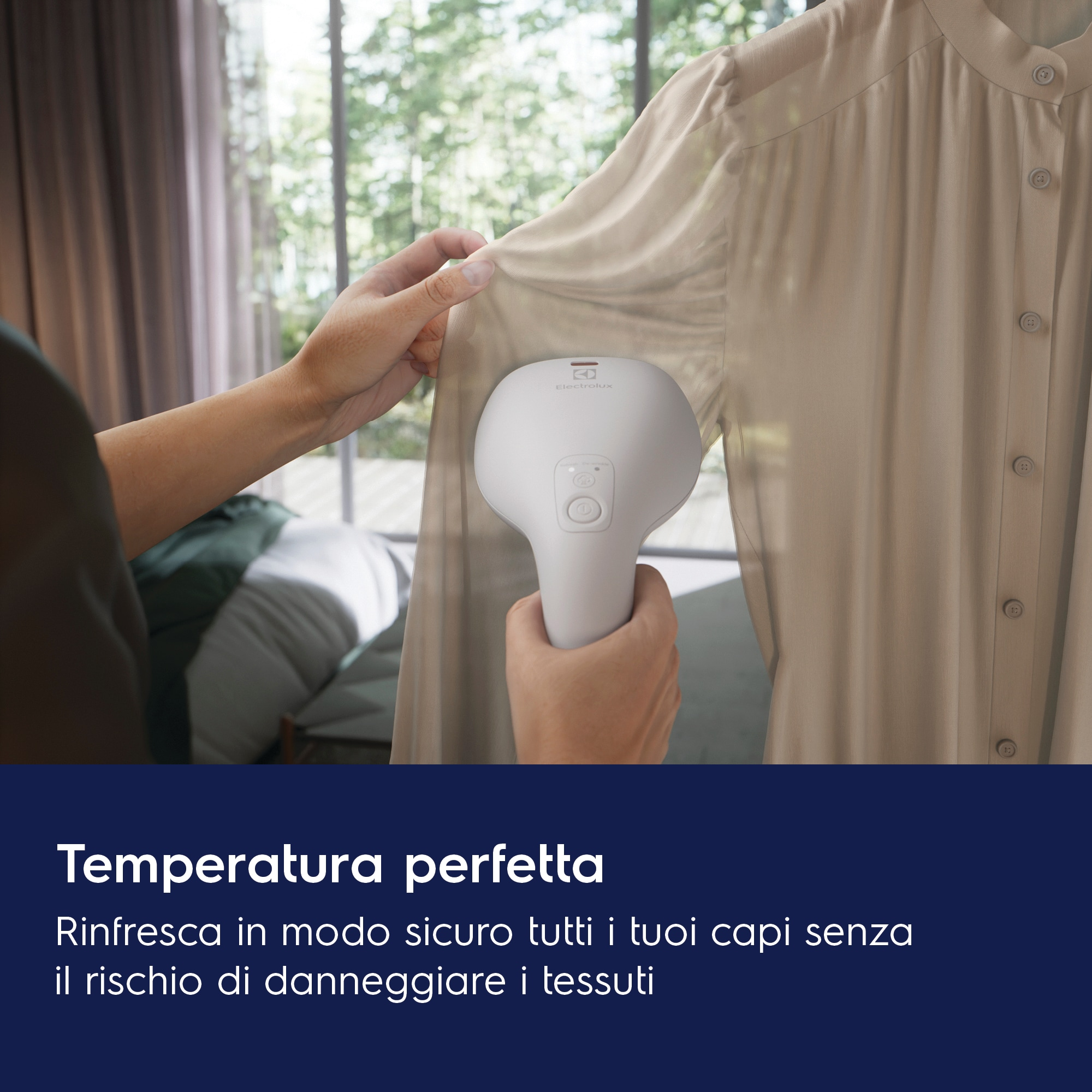 Una persona usa un vaporizzatore per indumenti bianco su una camicia beige. Lo sfondo è una finestra e una tenda.
