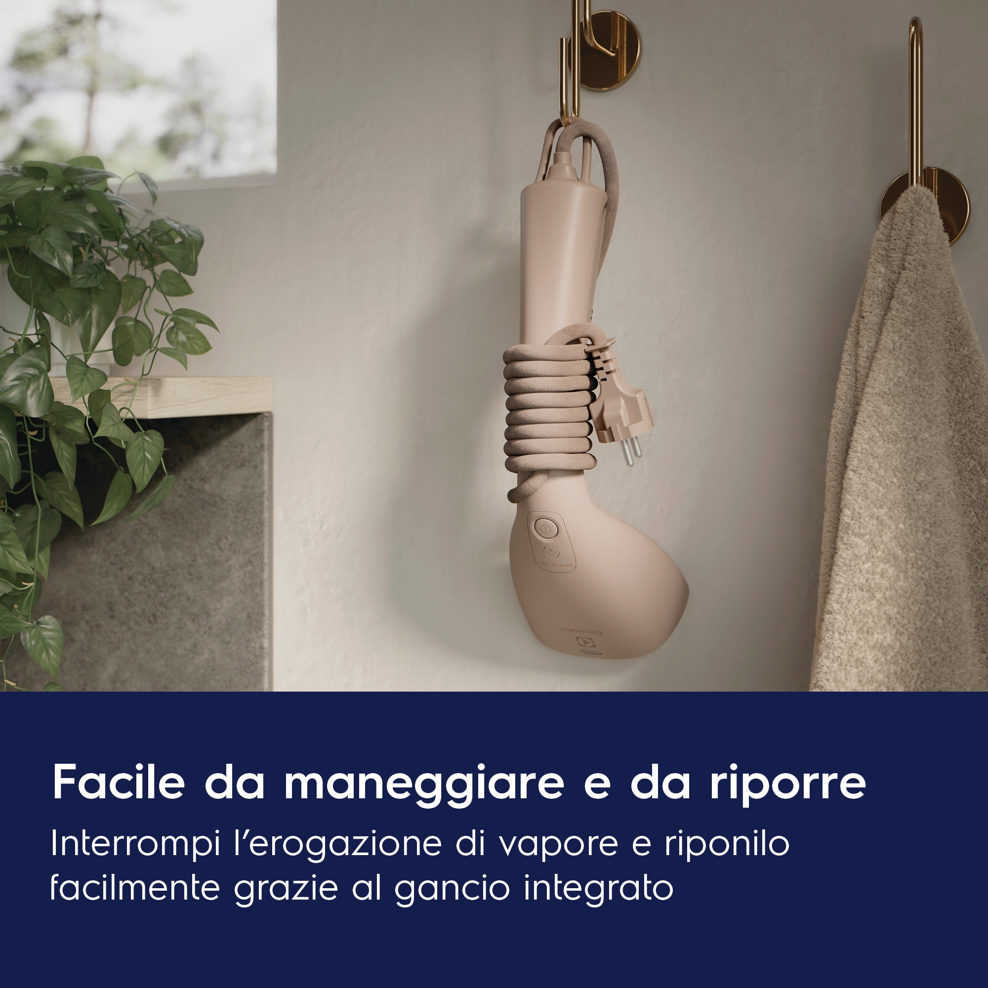 Un vaporizzatore portatile bianco appeso a un gancio a muro. Il cavo è arrotolato. Un asciugamano è appeso vicino.