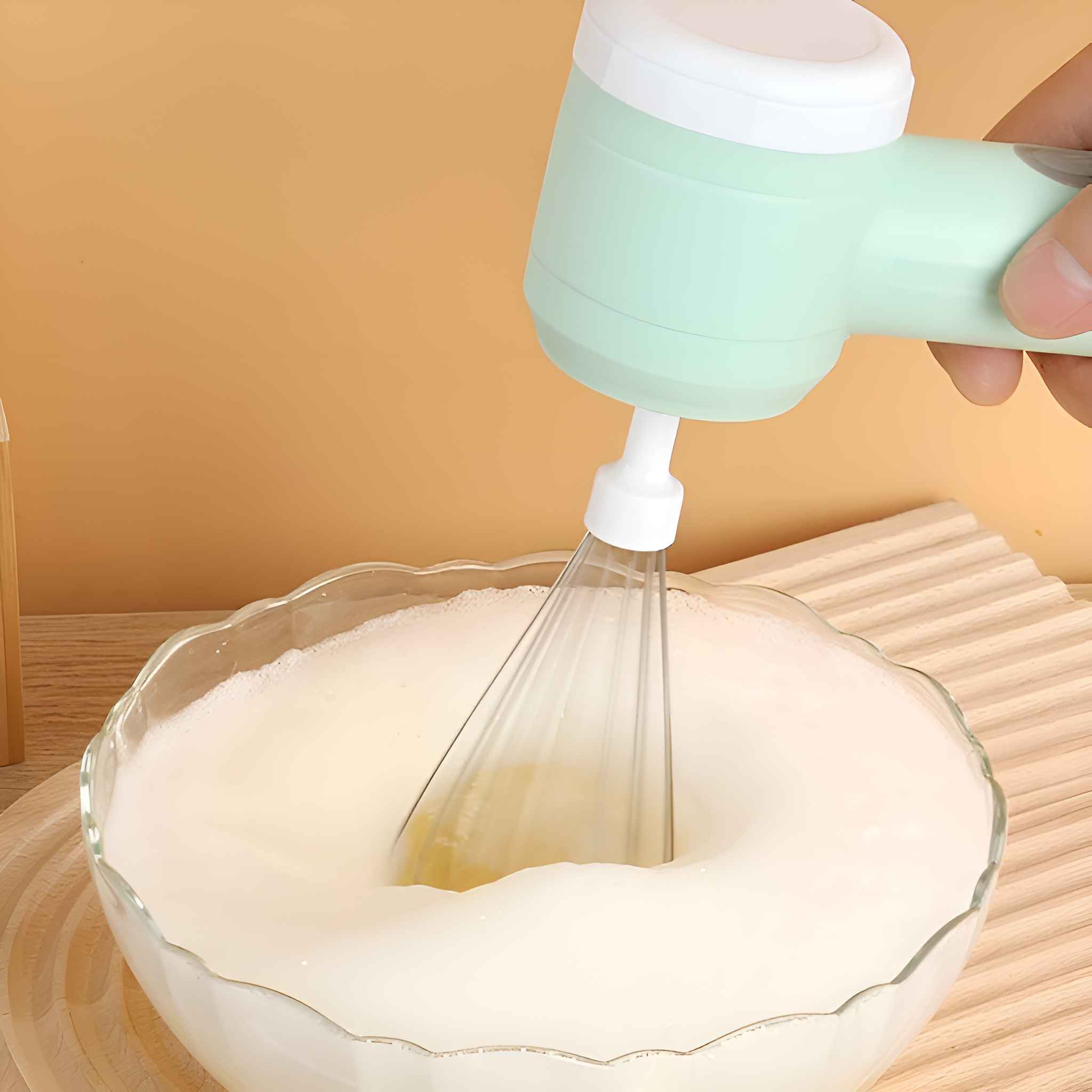 Ein Handmixer verrührt eine Schüssel mit weißer Flüssigkeit. Der Mixer ist grün und weiß.