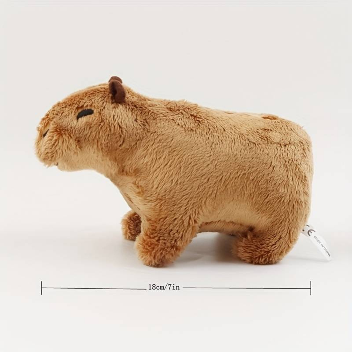 Ein braunes Capybara-Plüschtier. Es ist eine Seitenansicht, die kleine Ohren und Augen sowie ein Etikett an der Seite zeigt.