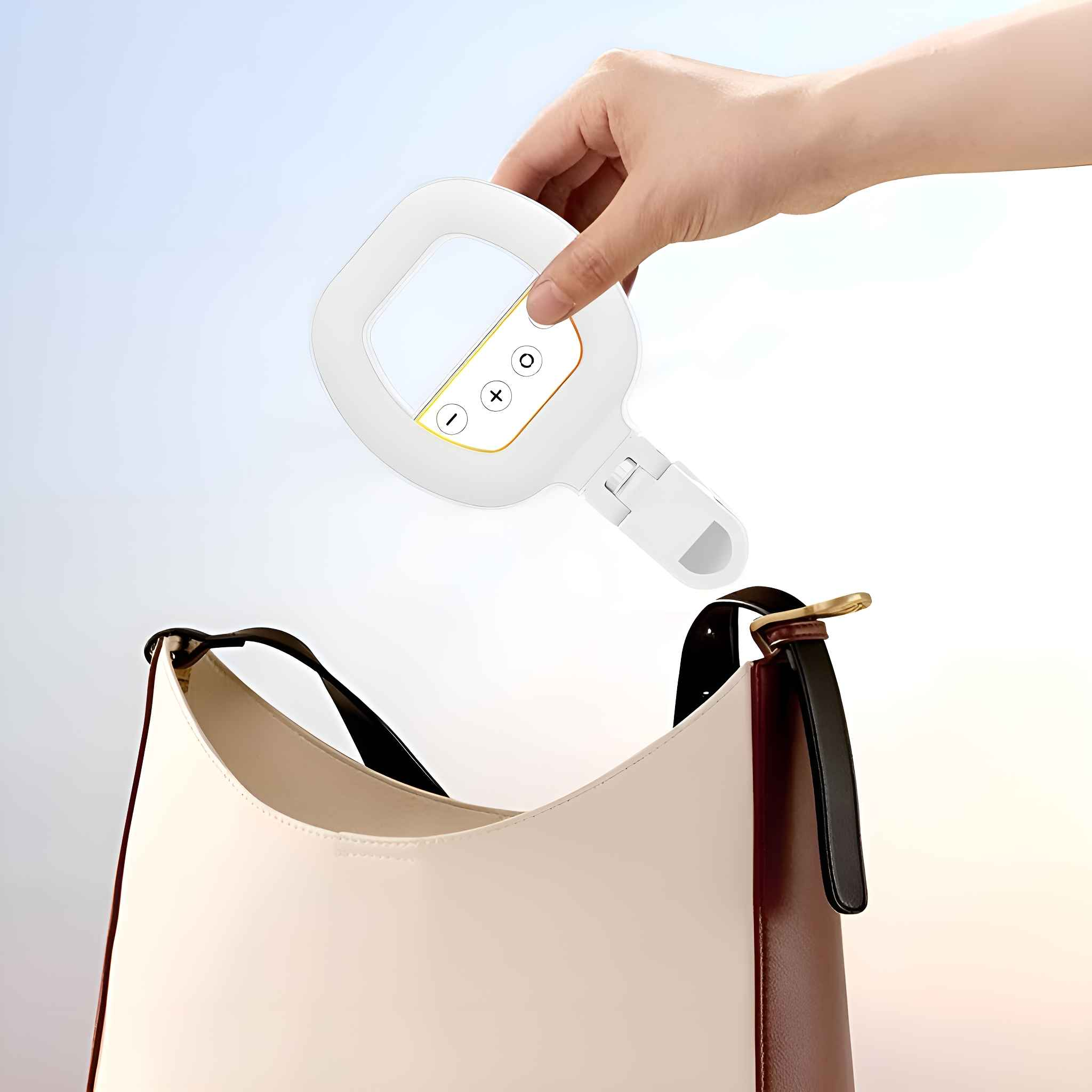 Eine Hand legt ein Ringlicht in eine Handtasche. Der Hintergrund ist ein heller, sonniger Himmel.