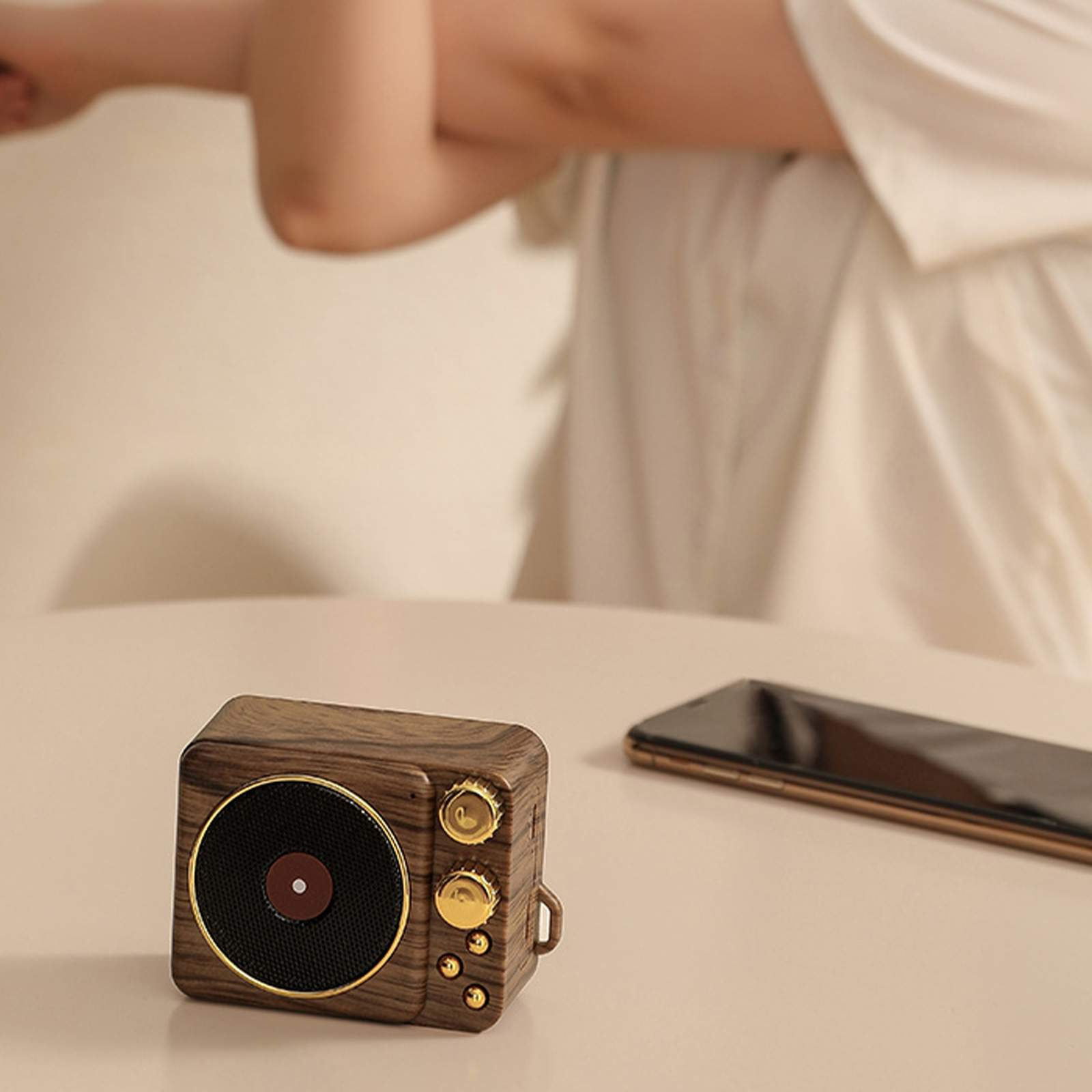 Retro-Lautsprecher auf einem Tisch neben einem Telefon. Der Lautsprecher ist aus Holz mit goldenen Akzenten.