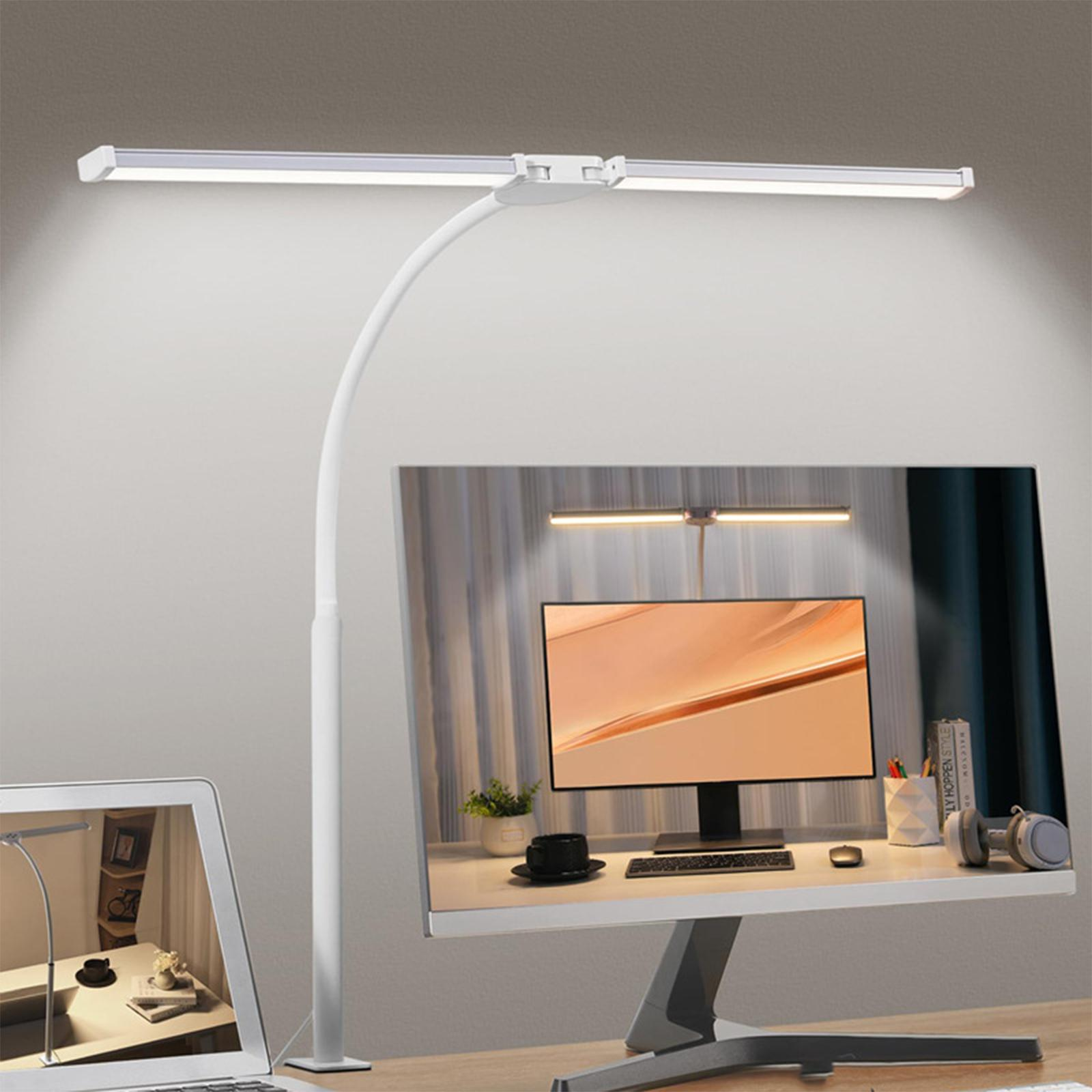 Eine weiße Schreibtischlampe beleuchtet einen Schreibtisch mit Monitor, Laptop und anderen Gegenständen. Licht.