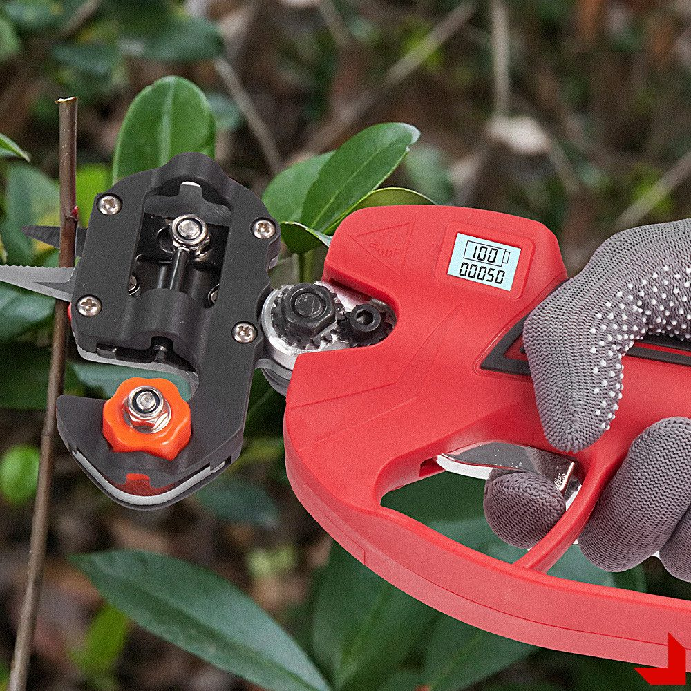 Rote und schwarze elektrische Baumschere schneidet einen Ast. Behandschuhte Hand hält das Werkzeug.