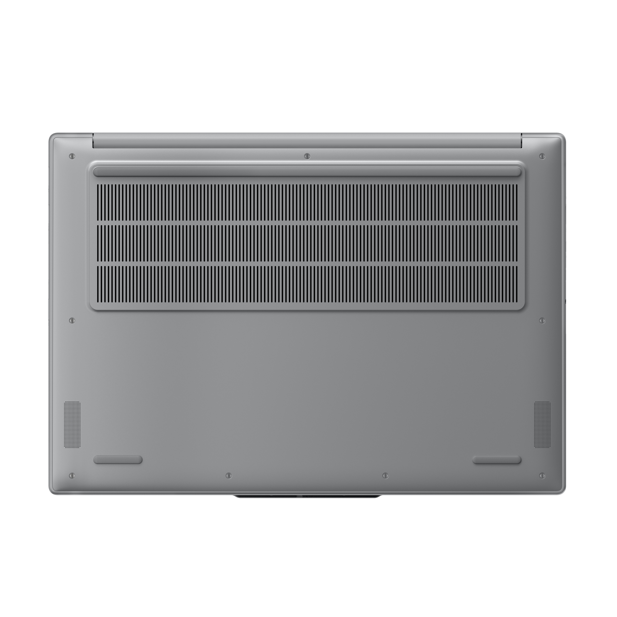 Spód srebrnego laptopa, pokazujący otwory wentylacyjne i gumowe nóżki. Białe tło.