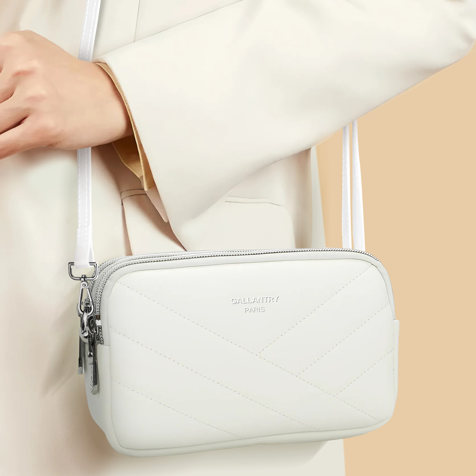 Una persona sosteniendo un bolso blanco con correa de cadena plateada. La marca es visible.