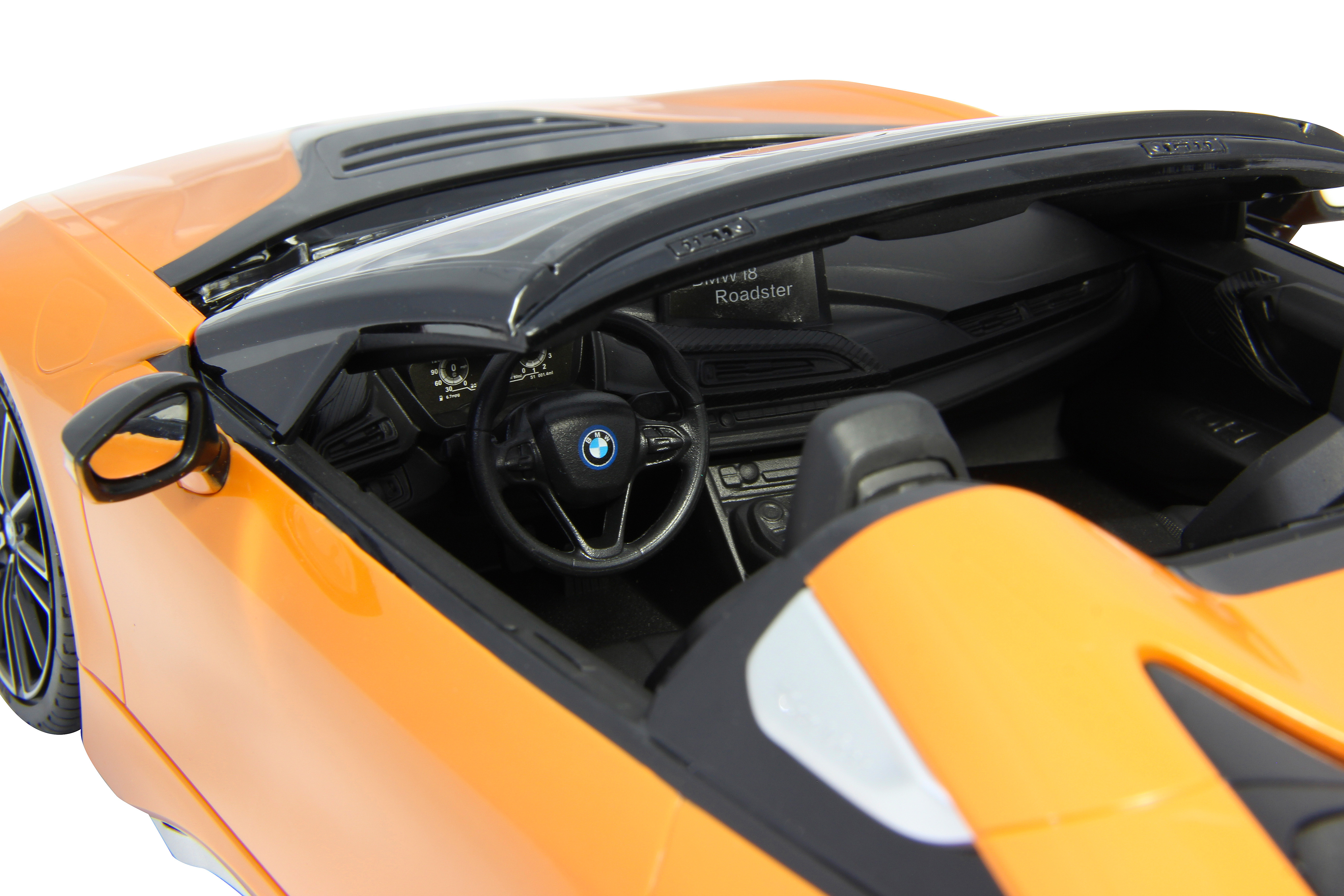 Innenansicht eines orangefarbenen BMW i8 Roadster Spielzeugautos. Armaturenbrett, Lenkrad und Sitze sind sichtbar.