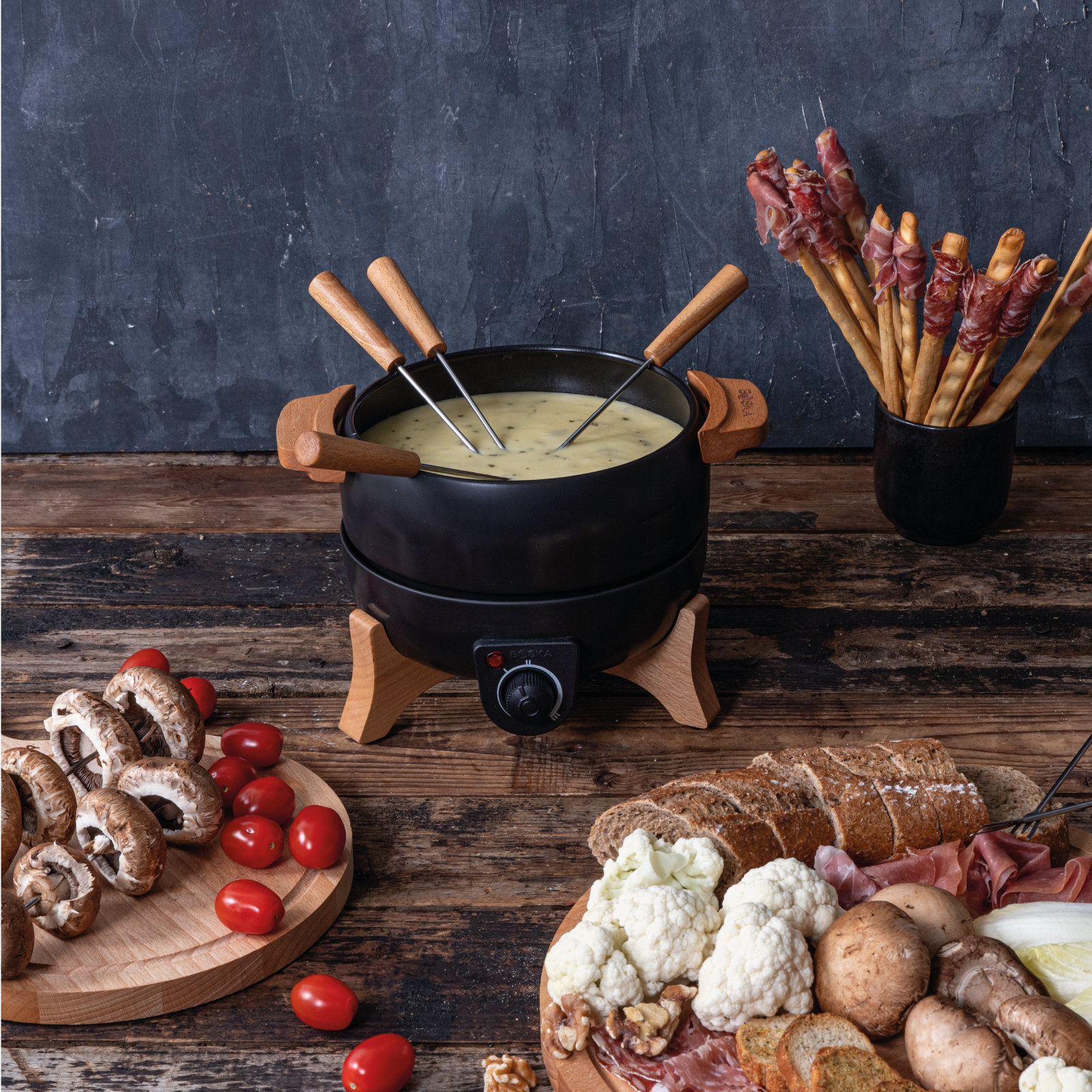 A fondue set with cheese, vegetables, and bread.