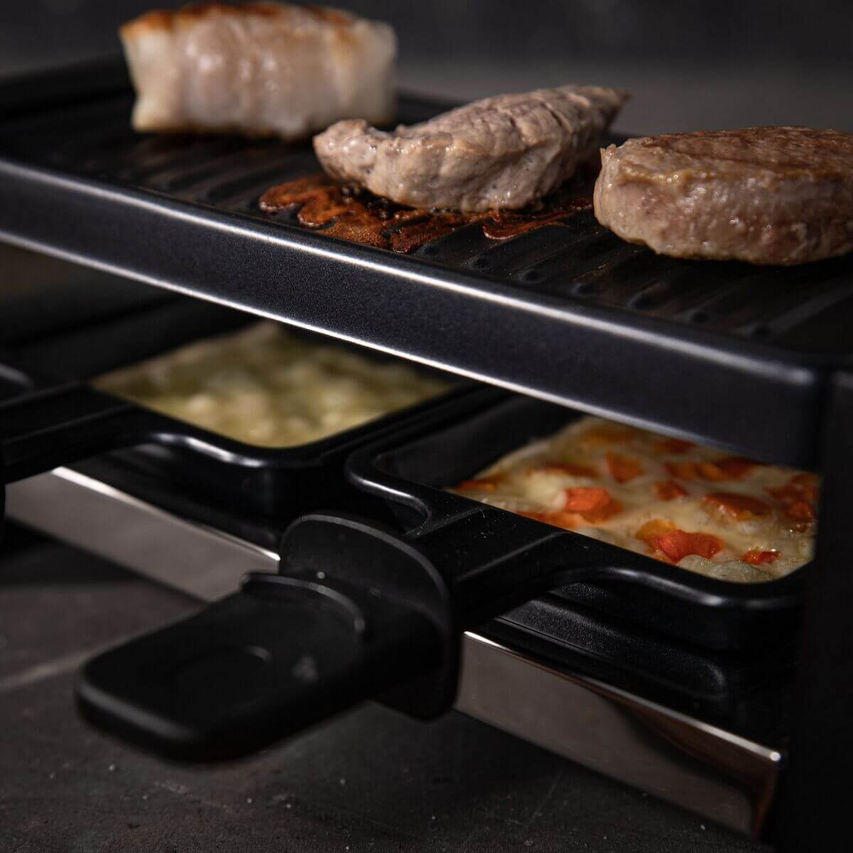 Close up of a raclette grill with cheese and meat.