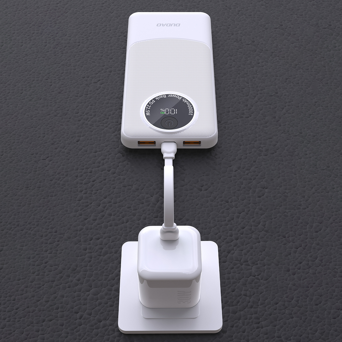 Biały power bank w trakcie ładowania, podłączony do białej ładowarki ściennej na ciemnoszarej powierzchni.