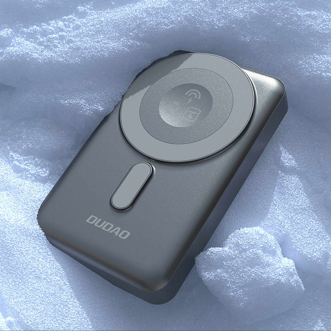 Szara podkładka ładująca leży na śniegu. Podkładka ma symbol ładowania i napis "DUDAO".