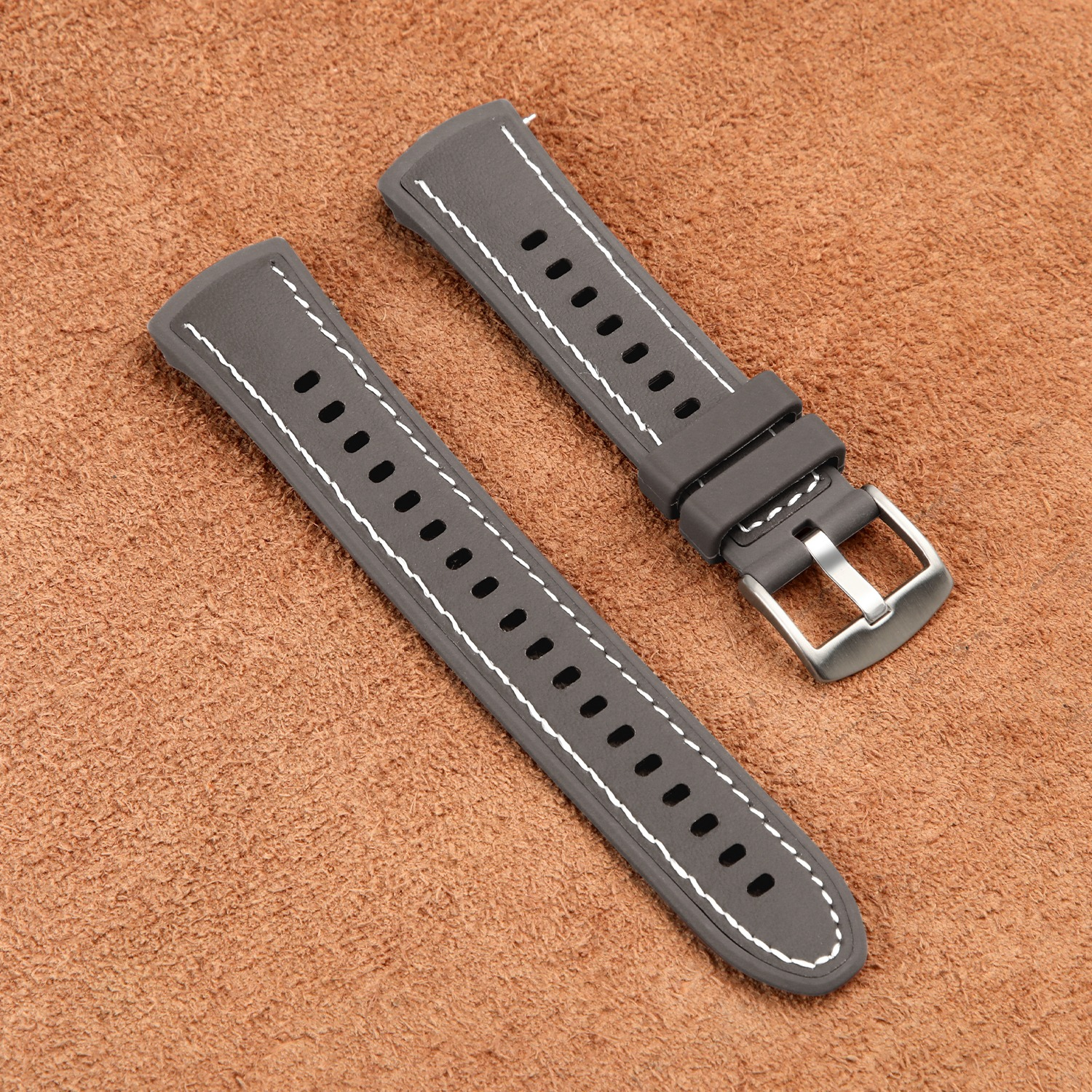 Cinturini grigi per smartwatch con cuciture bianche su una superficie marrone strutturata.