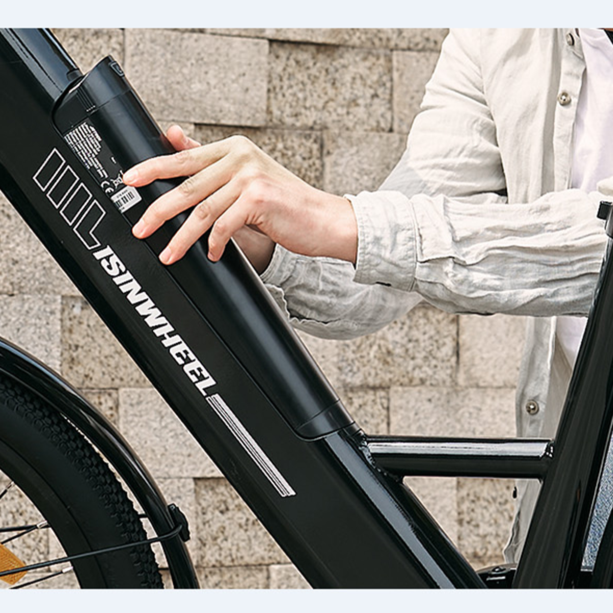 Dłoń instalująca czarną baterię na czarno-srebrnej ramie roweru elektrycznego.