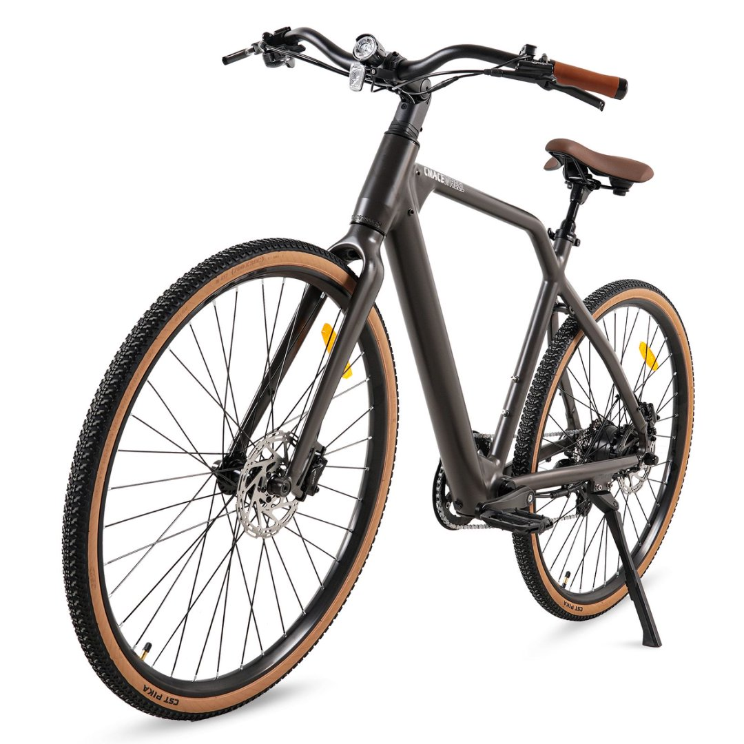 Szary rower z brązowym siodełkiem i kierownicą, beżowymi oponami. Nazwa marki na ramie. Ze stopką.