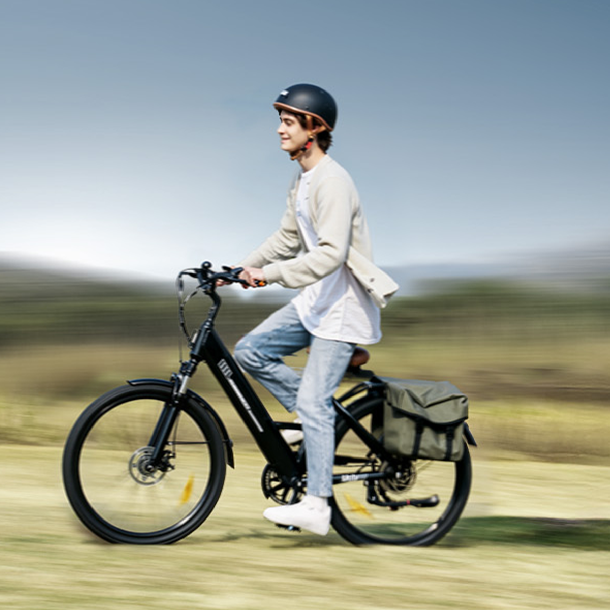 Mężczyzna jadący czarnym rowerem po trawiastym szlaku. Ma na sobie kask i ubrania codzienne.