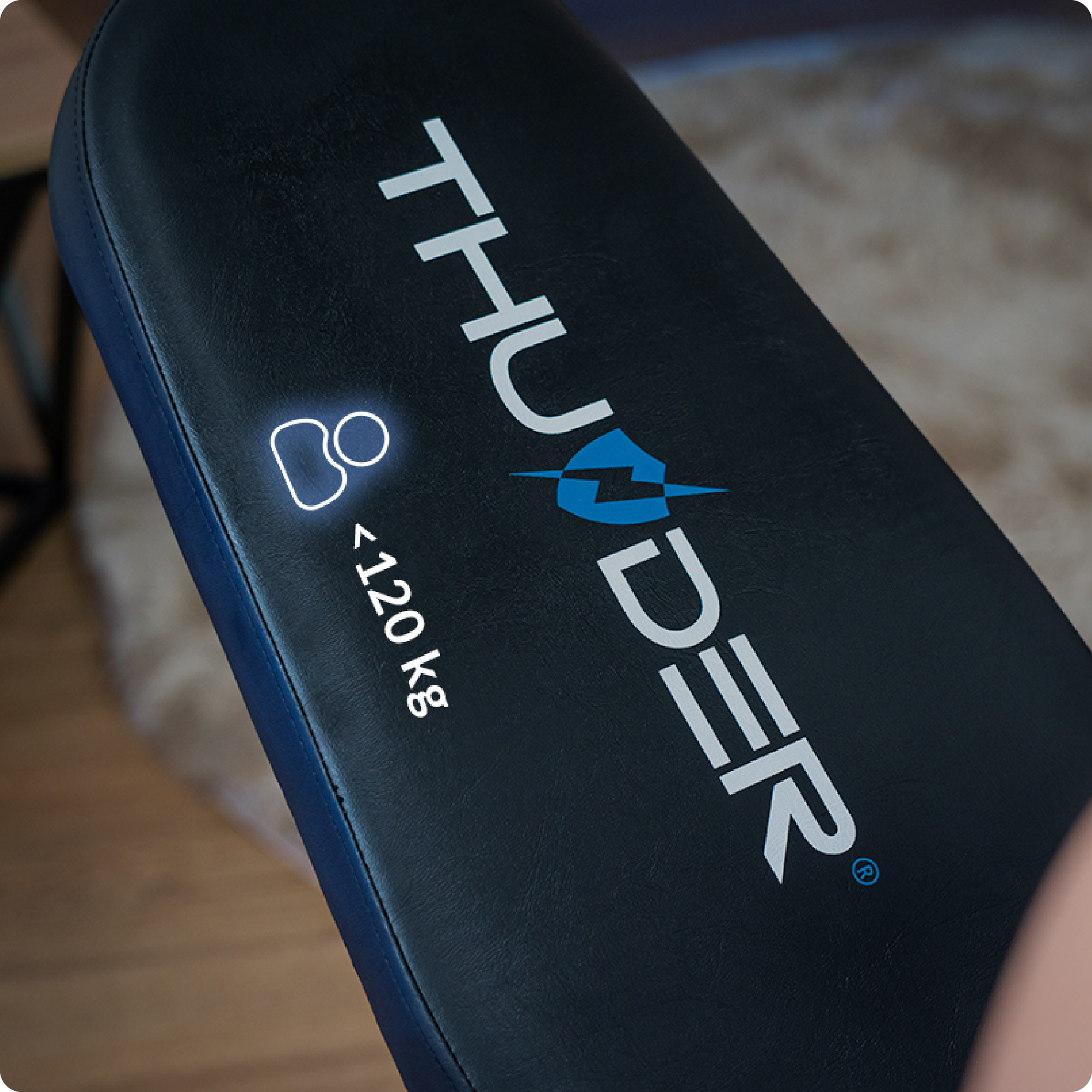 Zbliżenie na ławkę do ćwiczeń z logo. Ławka jest czarno-niebieska, z ograniczeniem wagowym.