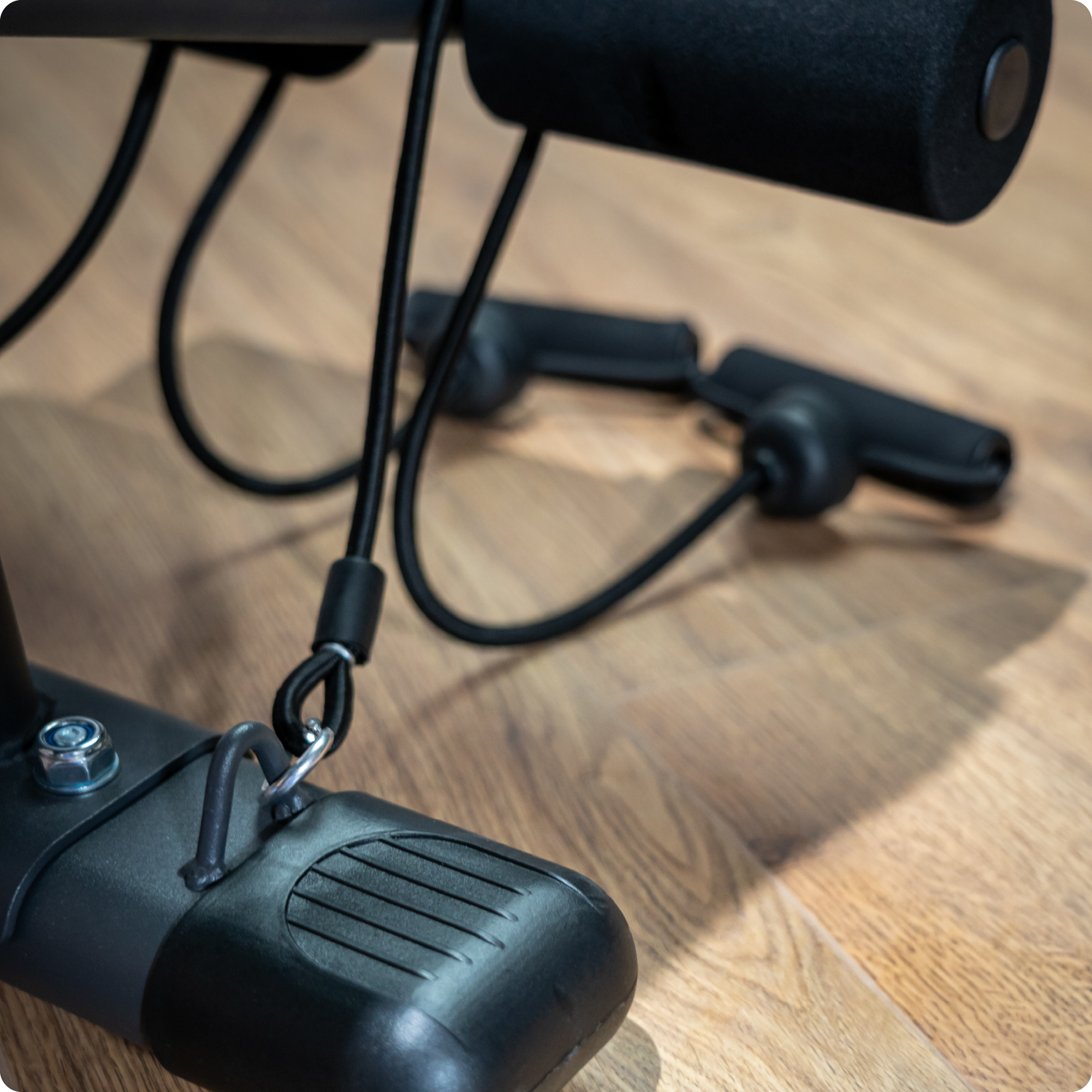 Zbliżenie na ławkę do ćwiczeń, w tym podpórkę na nogi i mocowanie kabla.