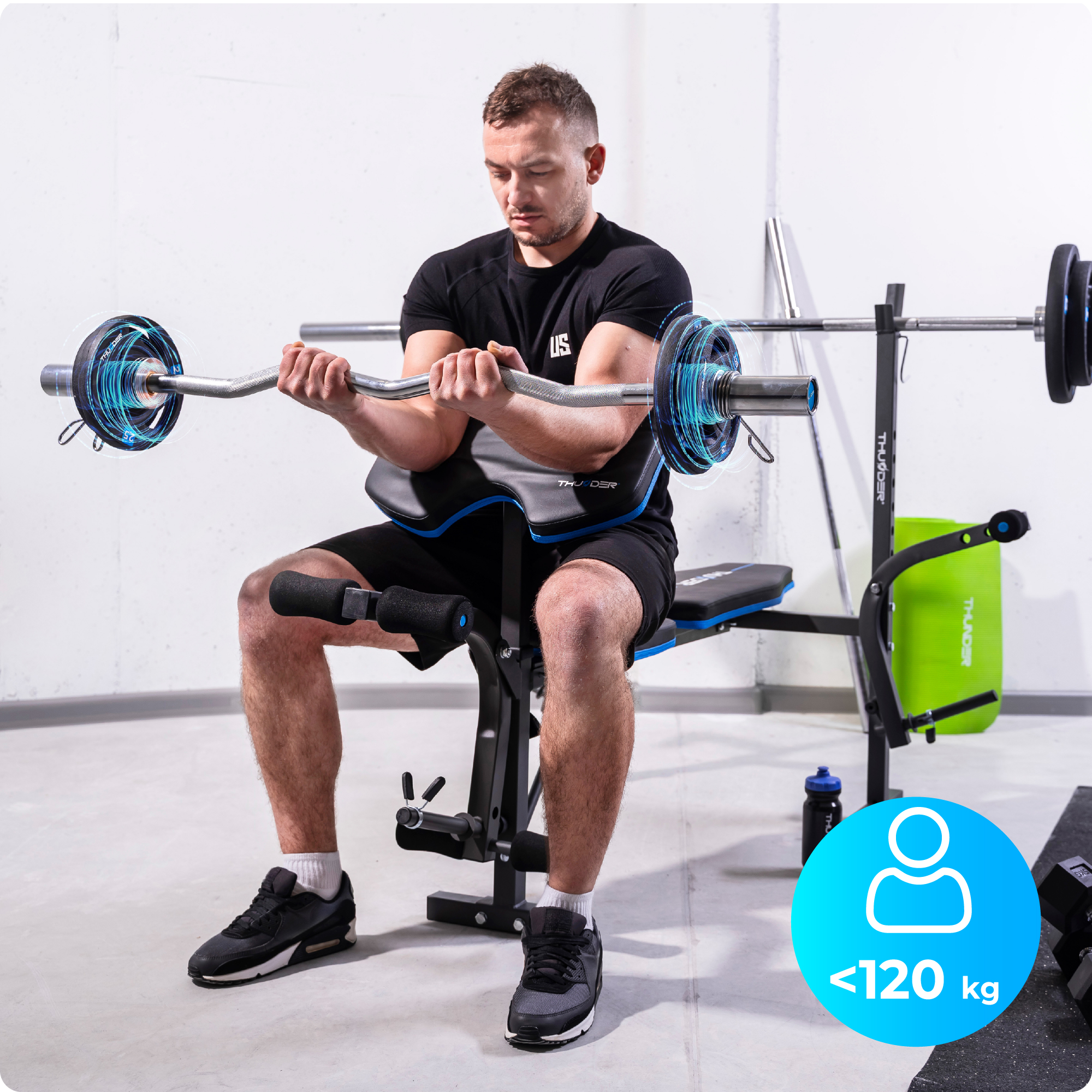 Mężczyzna siedzi na ławce do ćwiczeń, podnosząc ciężary. Ławka ma markę THUNDER. Udźwig wynosi poniżej 120 kg.
