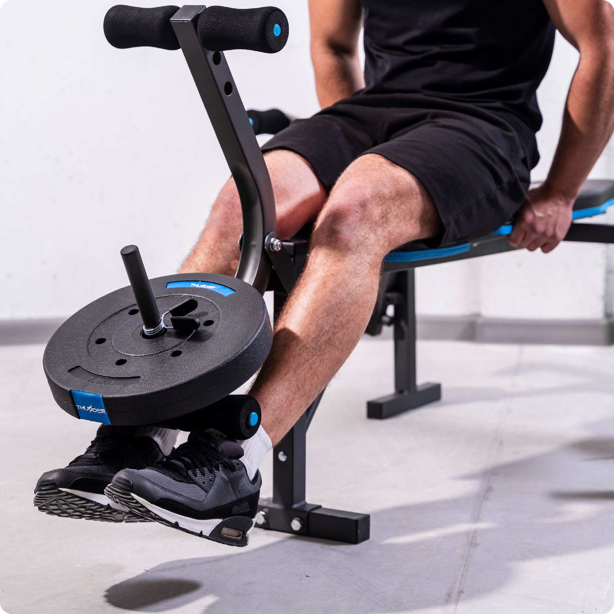 Mężczyzna używa maszyny do prostowania nóg. Maszyna ma markę THUNDER i dołączony jest talerz obciążeniowy.